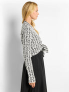 Off-white cardigan with black "BALANCE" lettering, long sleeves, and a tie waist.