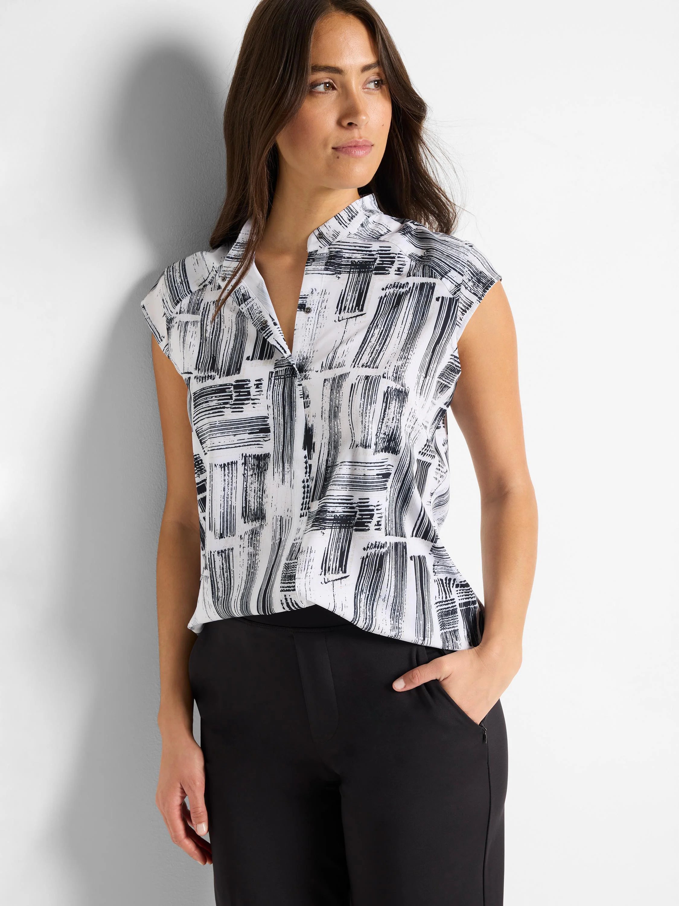 White sleeveless snap-neck top with black brushstroke pattern.