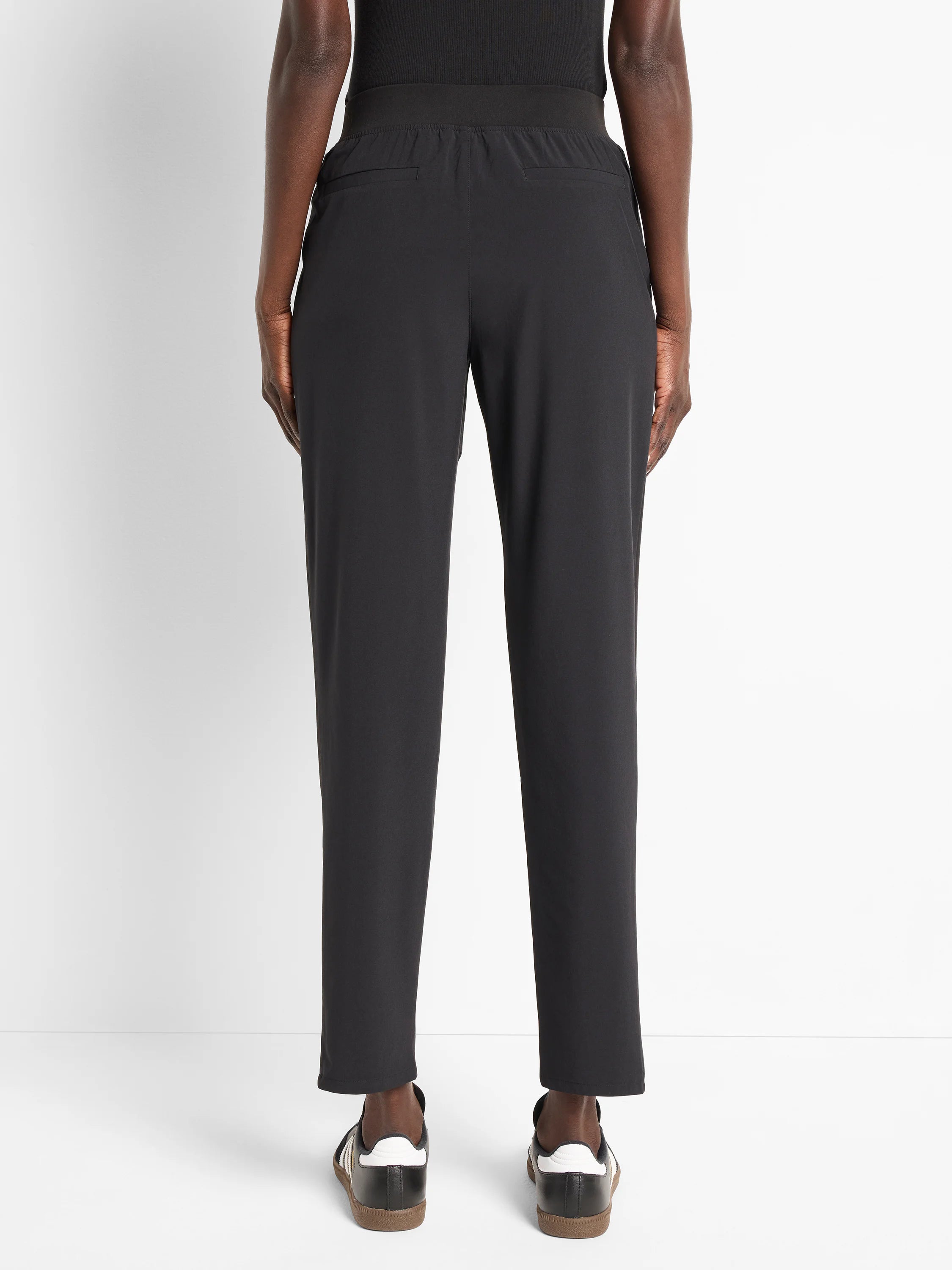 Black ankle-length pants with elastic waistband and back pockets. Model is wearing black shoes.