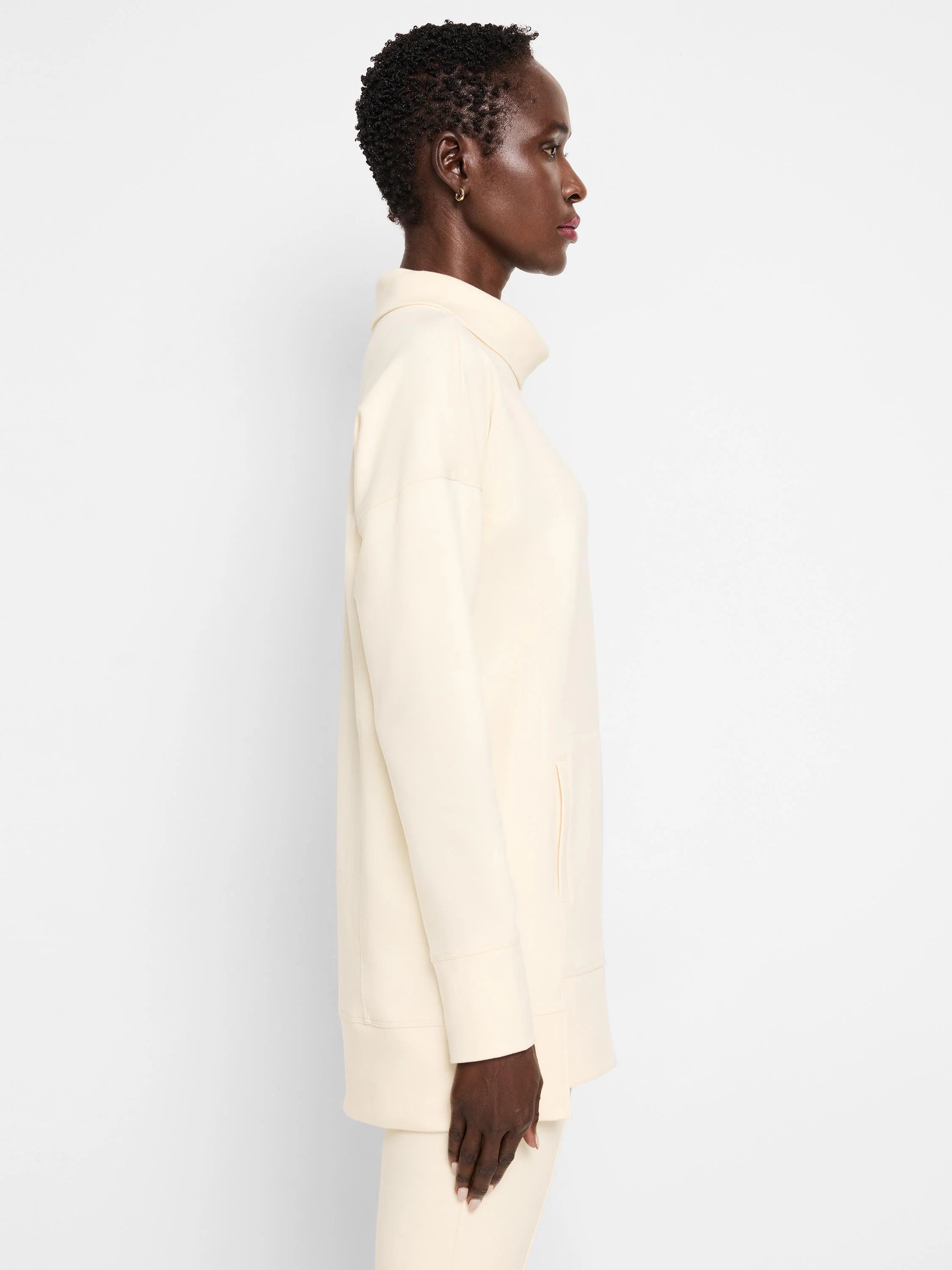 Off-white tunic with funnel neck, long sleeves, and a side pocket.
