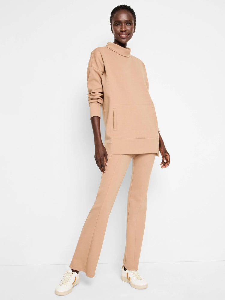 Beige tunic with funnel neck, long sleeves, and a kangaroo pocket. Matching pants are flared.