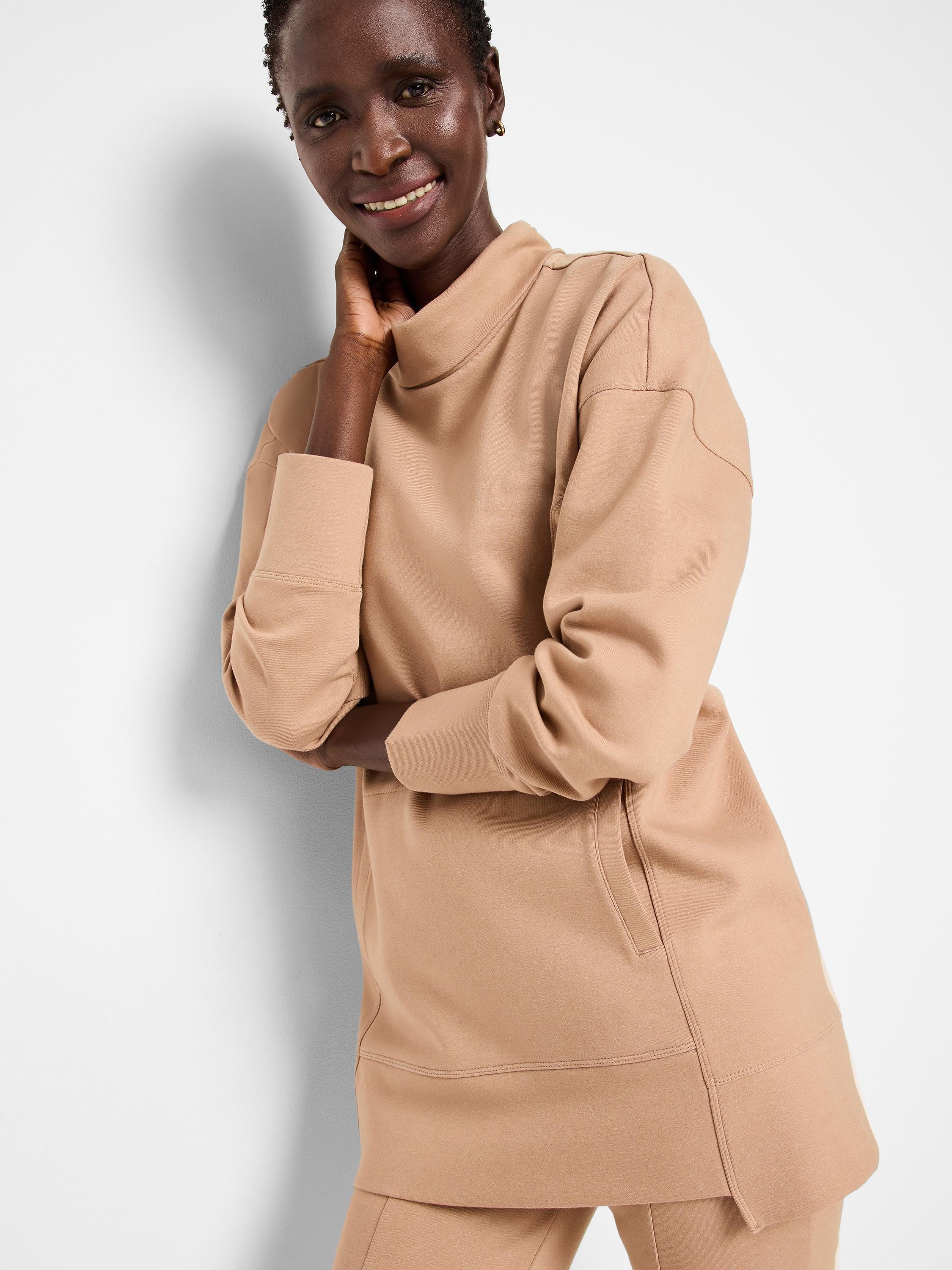 Light brown tunic with funnel neck, long sleeves, and side slits. Seams are visible.