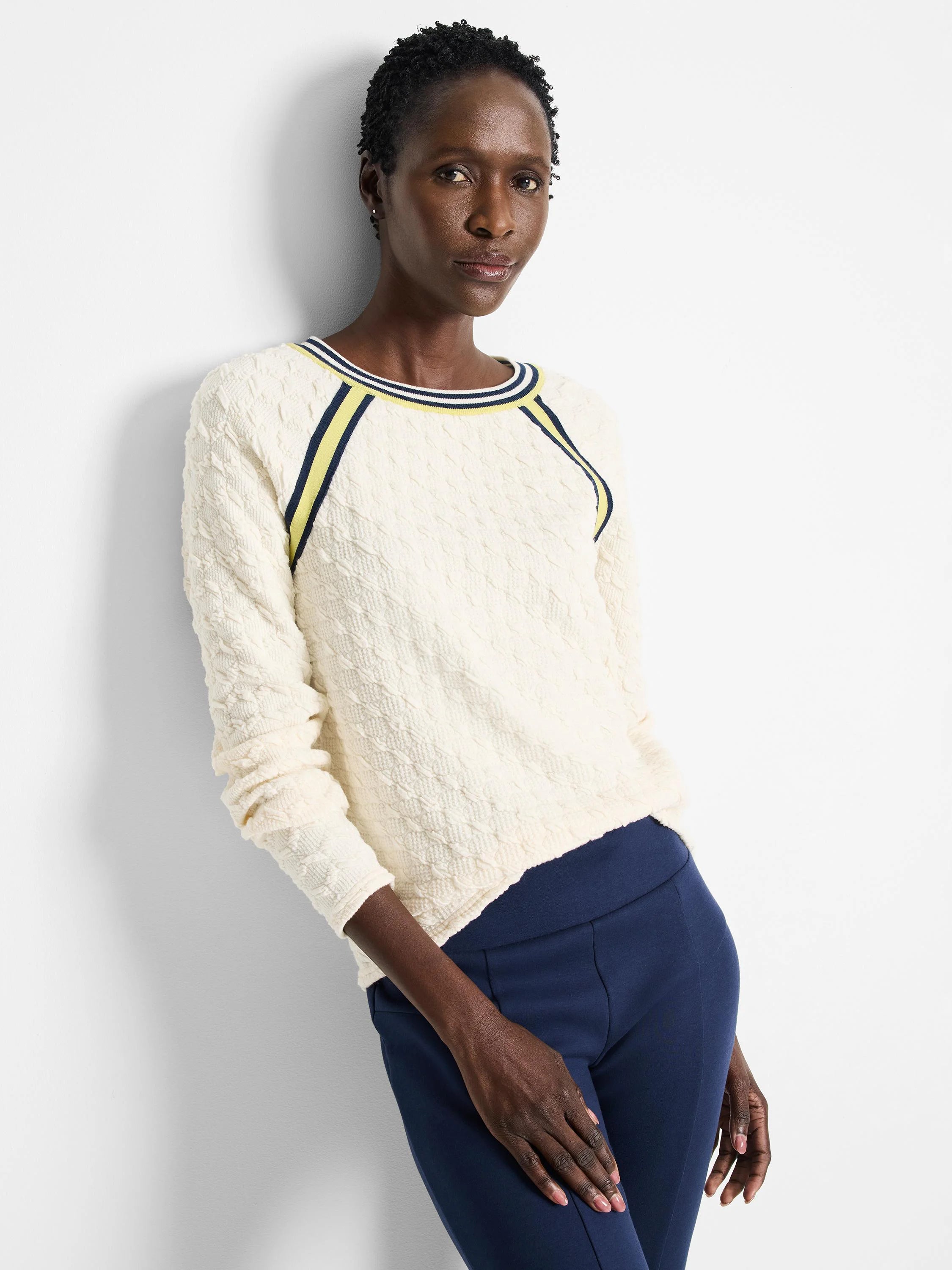 Off-white textured sweater with yellow and navy blue stripes at neckline and raglan sleeves.