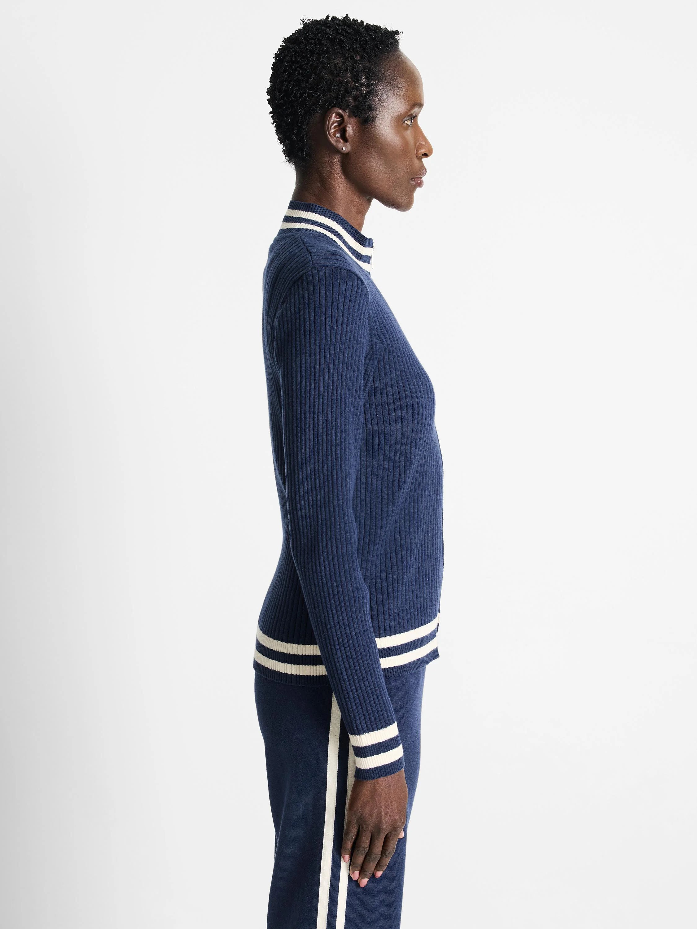 Navy blue ribbed knit track jacket. Off-white stripes at cuffs and hem. Zip front.