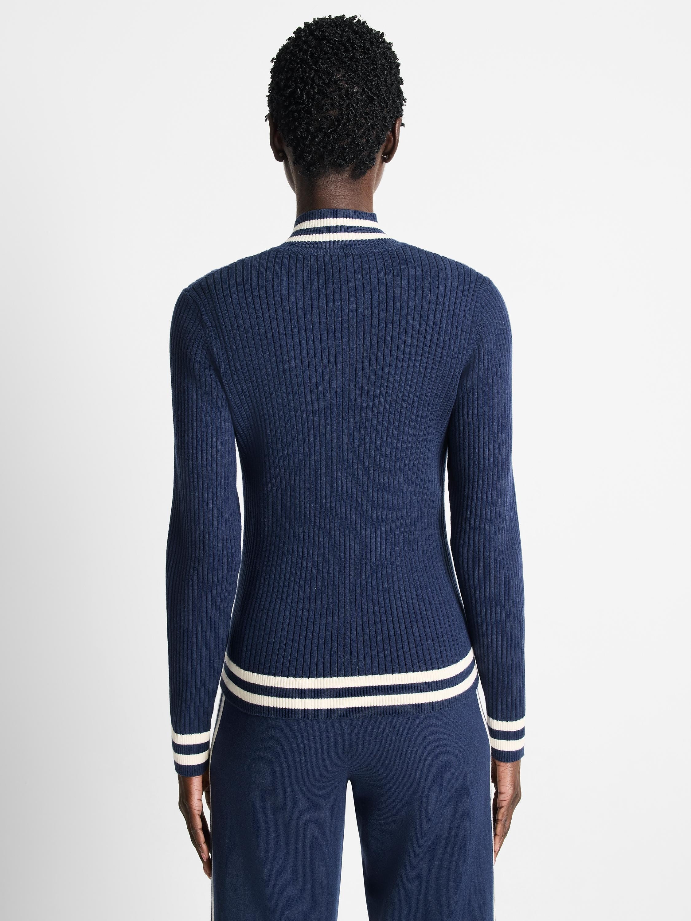 Navy blue ribbed knit track jacket with off-white/cream stripes at cuffs and hem. Shown from the back.