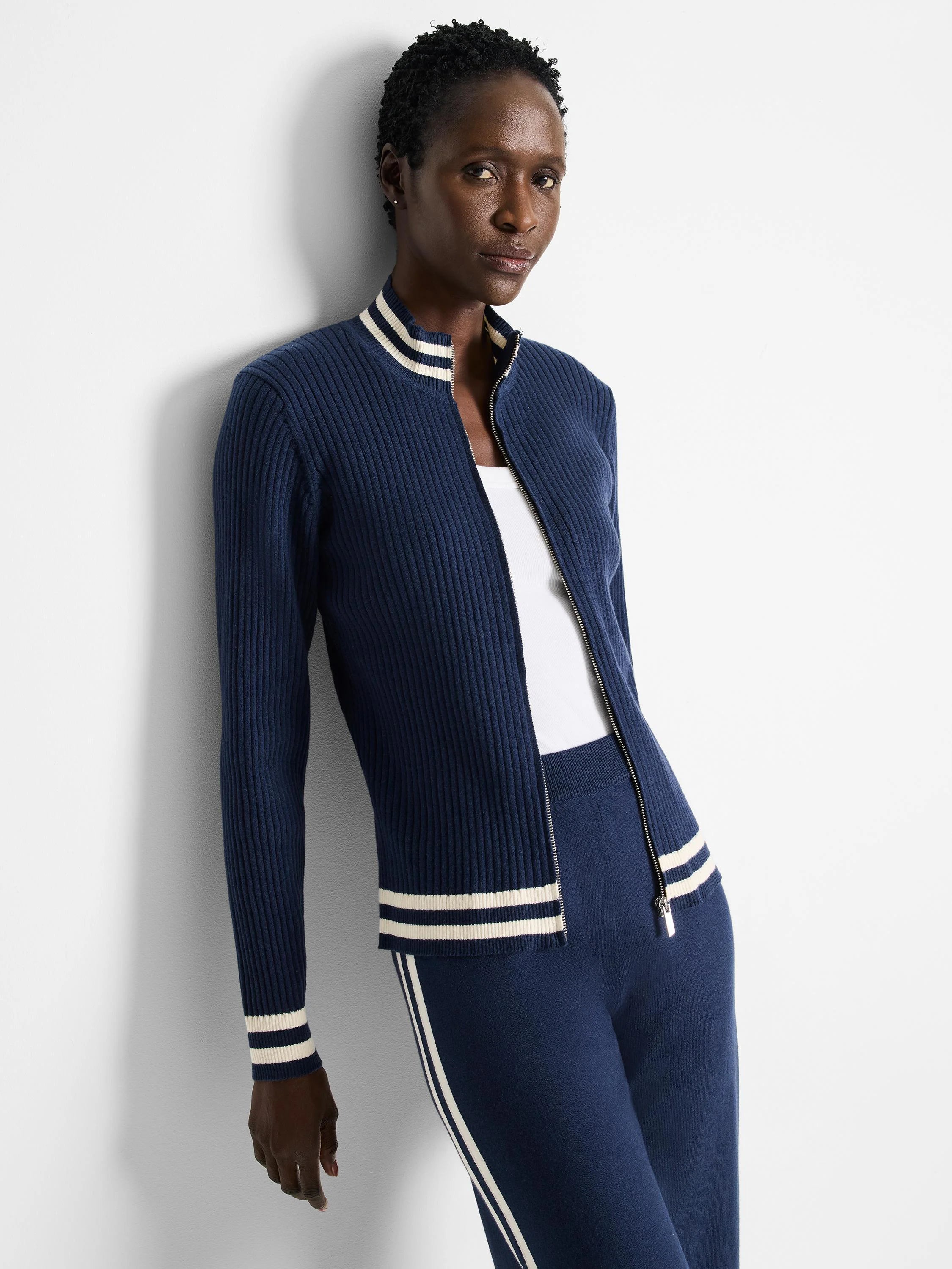 Navy blue ribbed knit zip-up track jacket with cream/off-white stripes at collar and cuffs.