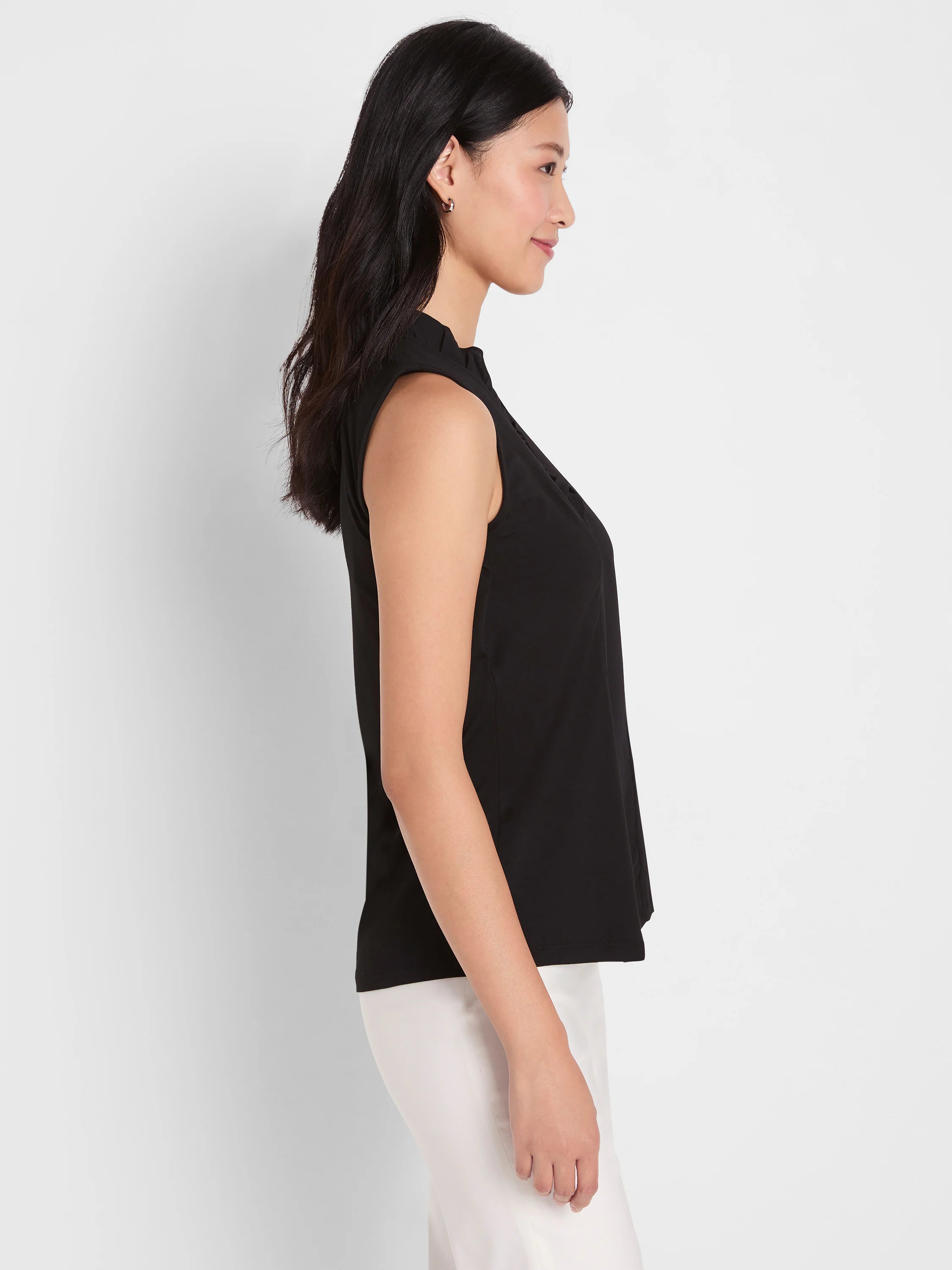 Black sleeveless tank with a ruffled stand collar, shown on a model in profile.
