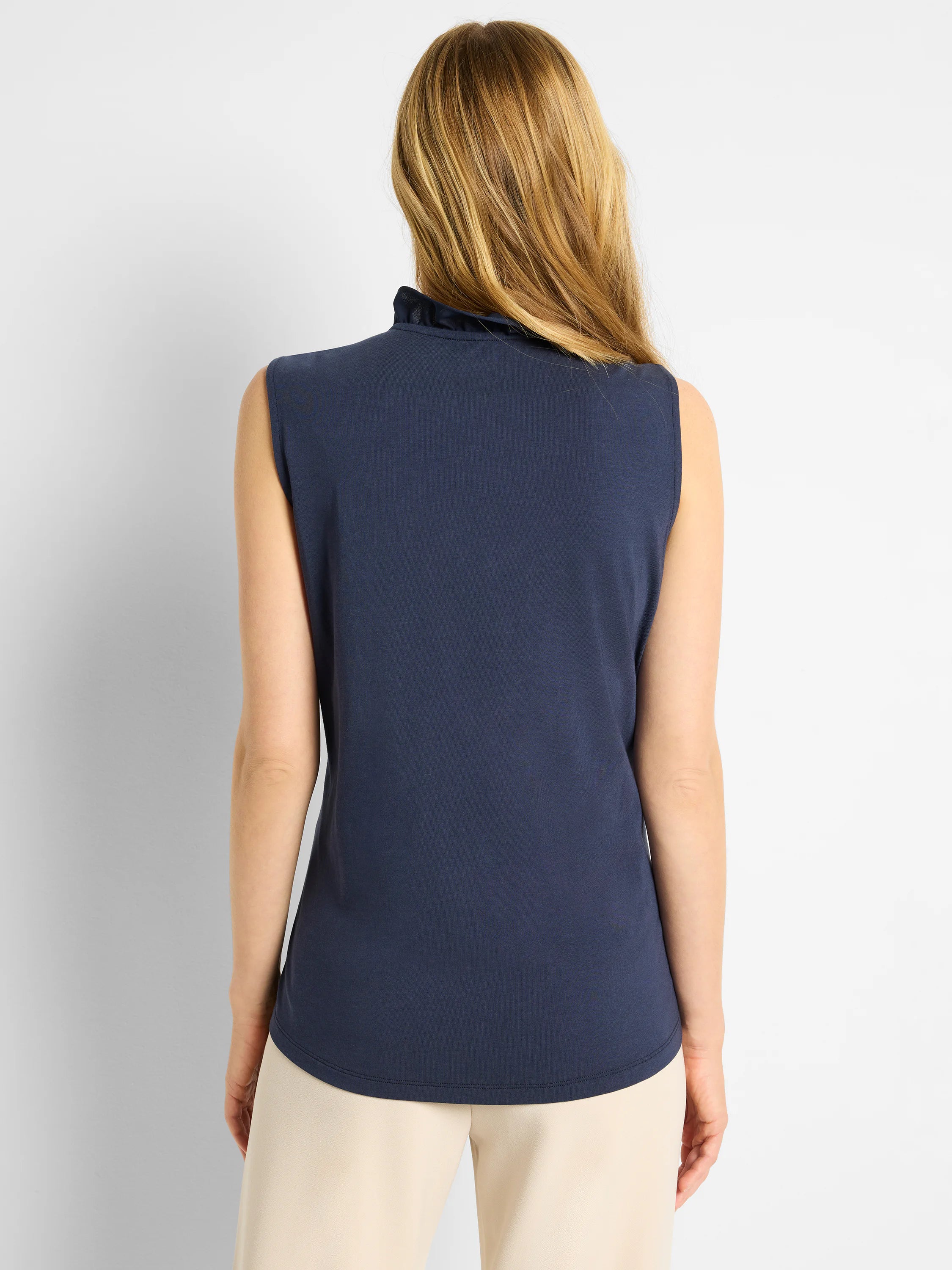 Navy sleeveless tank with ruffled stand-up collar and curved hem. Shown from the back.