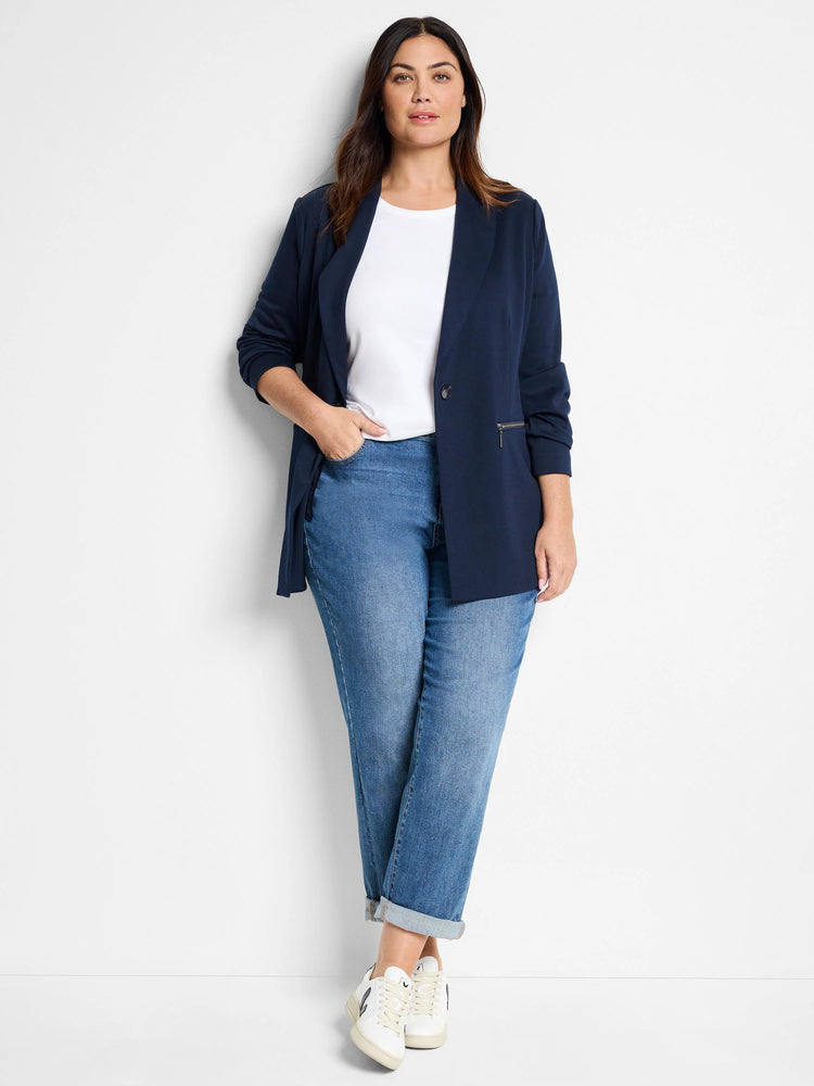 White crew neck knit t-shirt on a model, partially covered by a navy blazer.