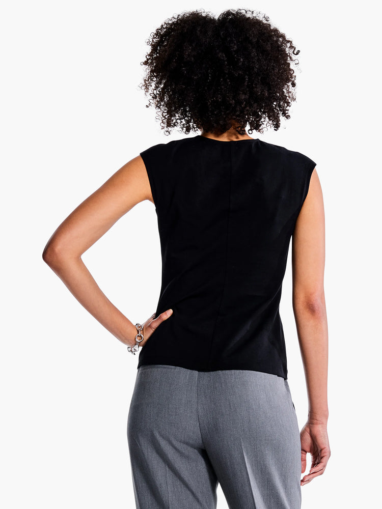 Black v-neck sleeveless top, shown from the back. Model also wears gray pants.