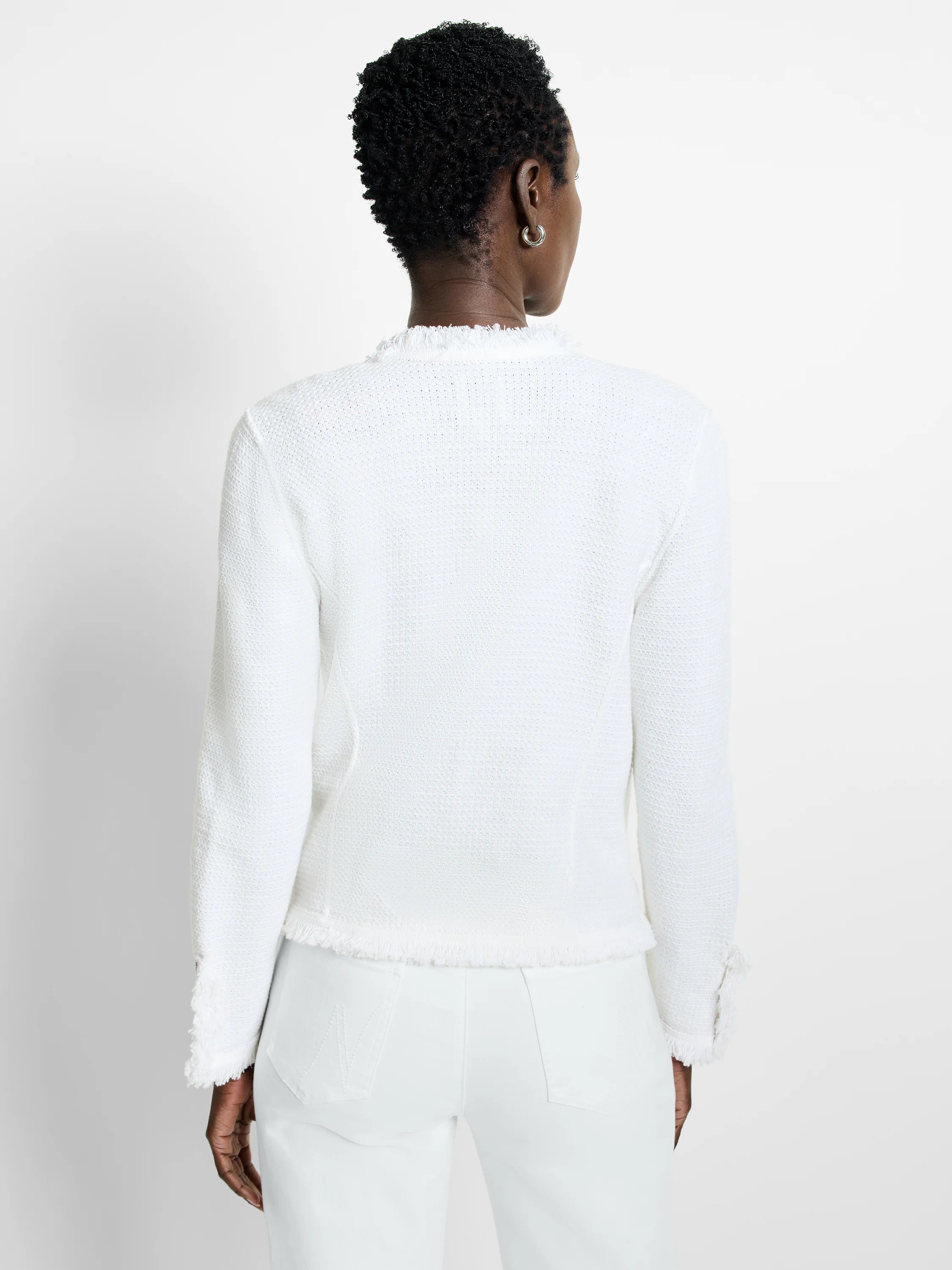 White textured knit jacket with fringe trim at the neckline, hem, and sleeve cuffs.
