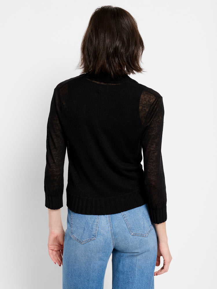 Black fitted sheer knit sweater features a high neck and 3/4 sleeves, paired with light wash jeans.