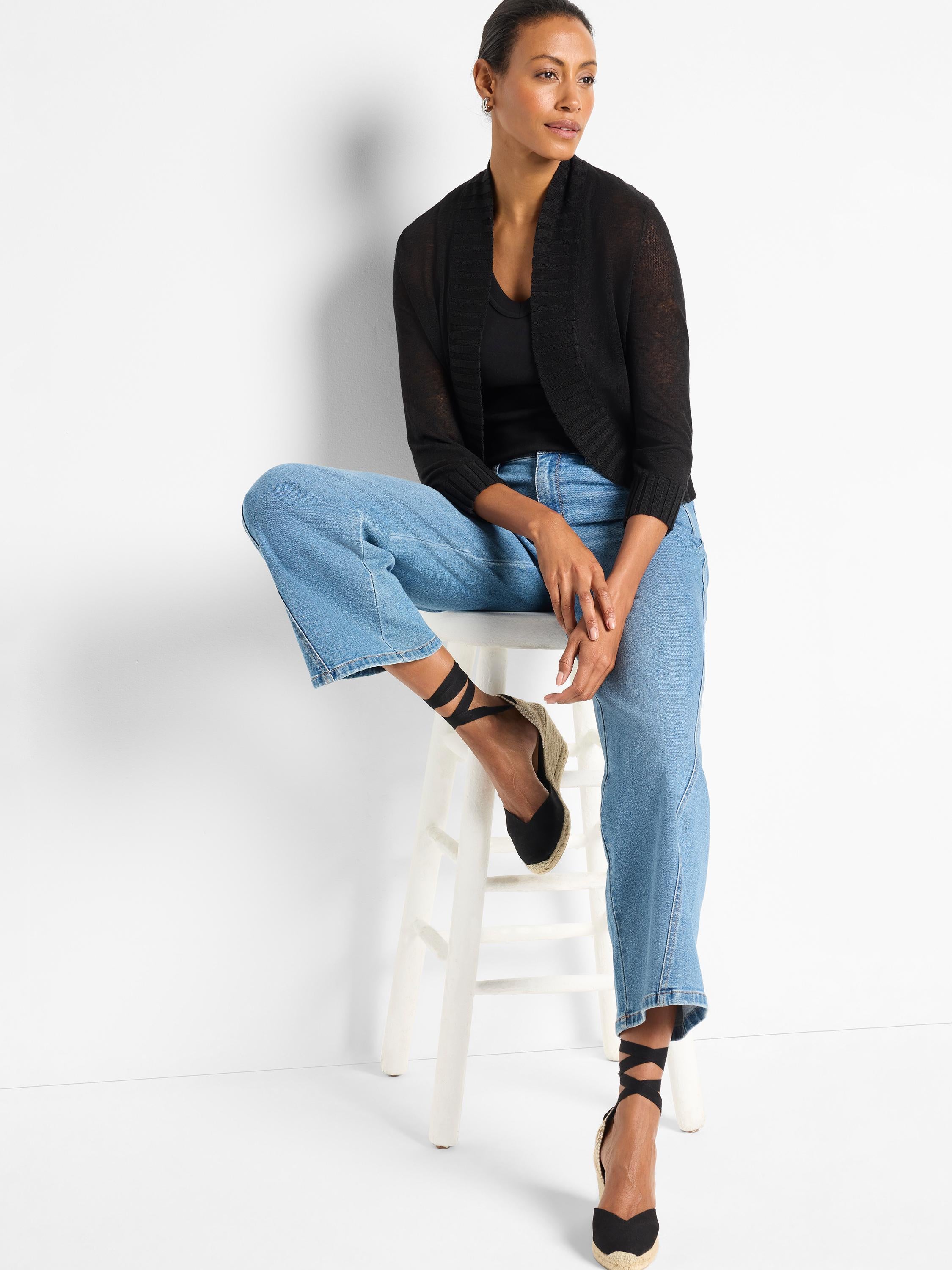 Black cropped knit bolero featuring sheer fabric, an open shawl front, and three-quarter length ribbed sleeves.