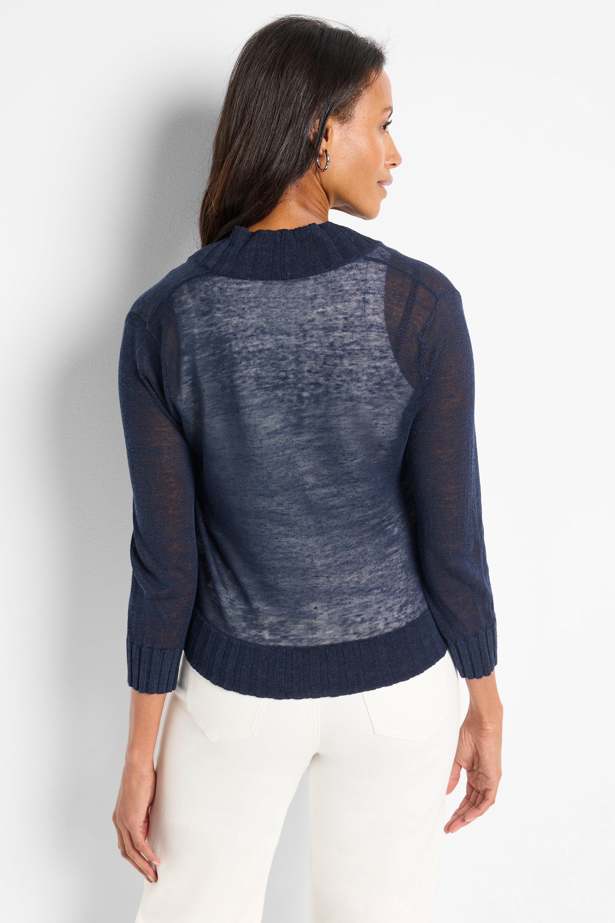 A sheer navy knit cropped sweater with three quarter sleeves and a mock neck is modeled.