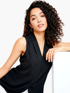 Black sleeveless V-neck top.  A woman models it.