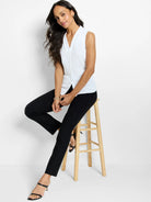 White sleeveless top with a folded V-neckline and a front seam ending in a small hem slit.