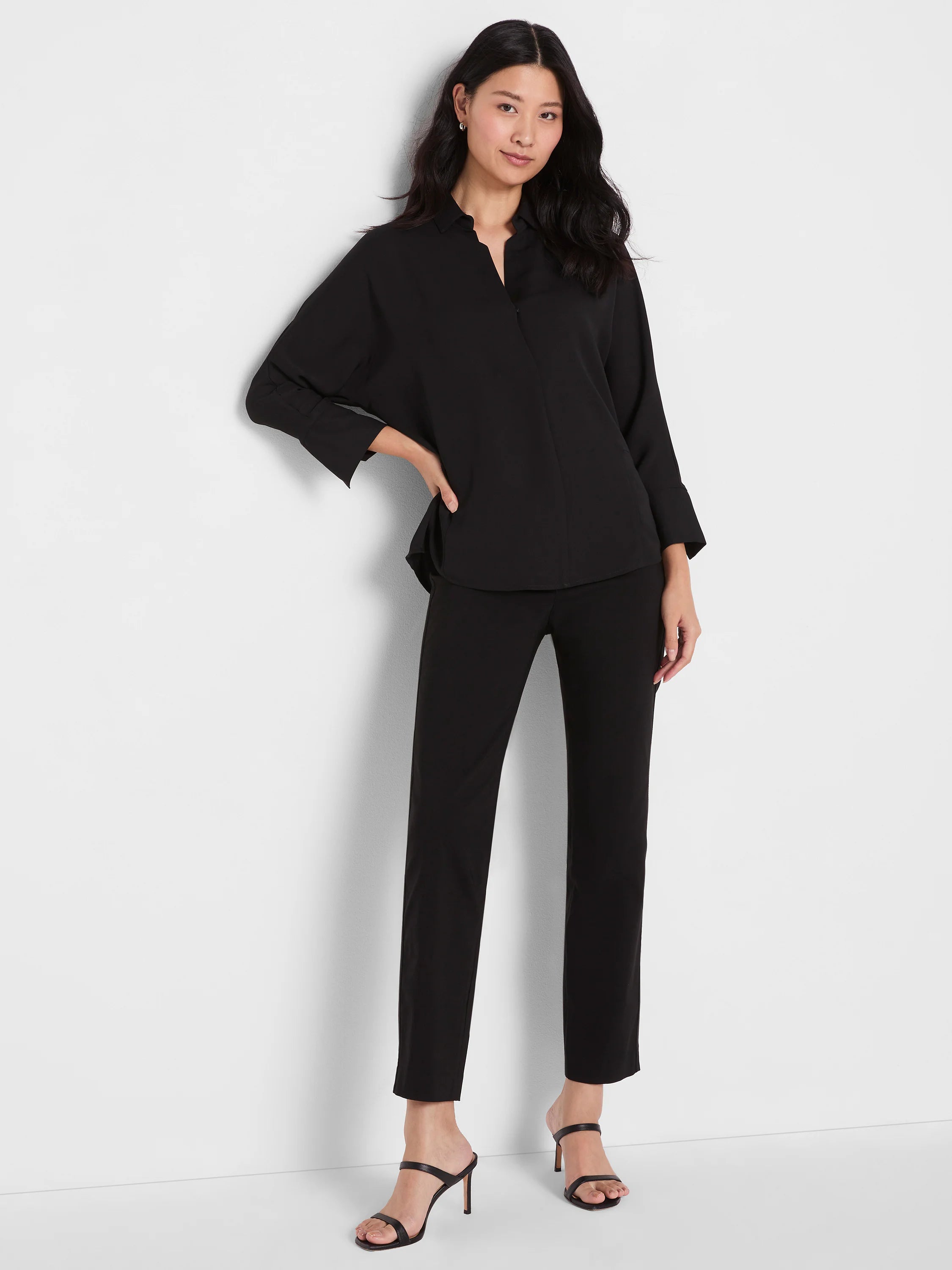 Black Flowing Ease Blouse with collared V-neck, relaxed fit, and long sleeves cuffed at the forearm.