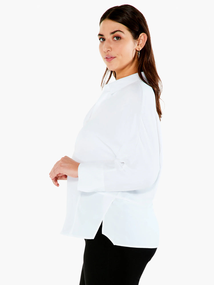 White, long-sleeve blouse. High neckline, relaxed fit, side slits.
