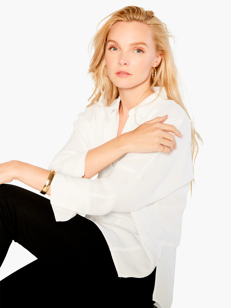White collared blouse; long sleeves; slightly loose fit. Model wears it with black pants.