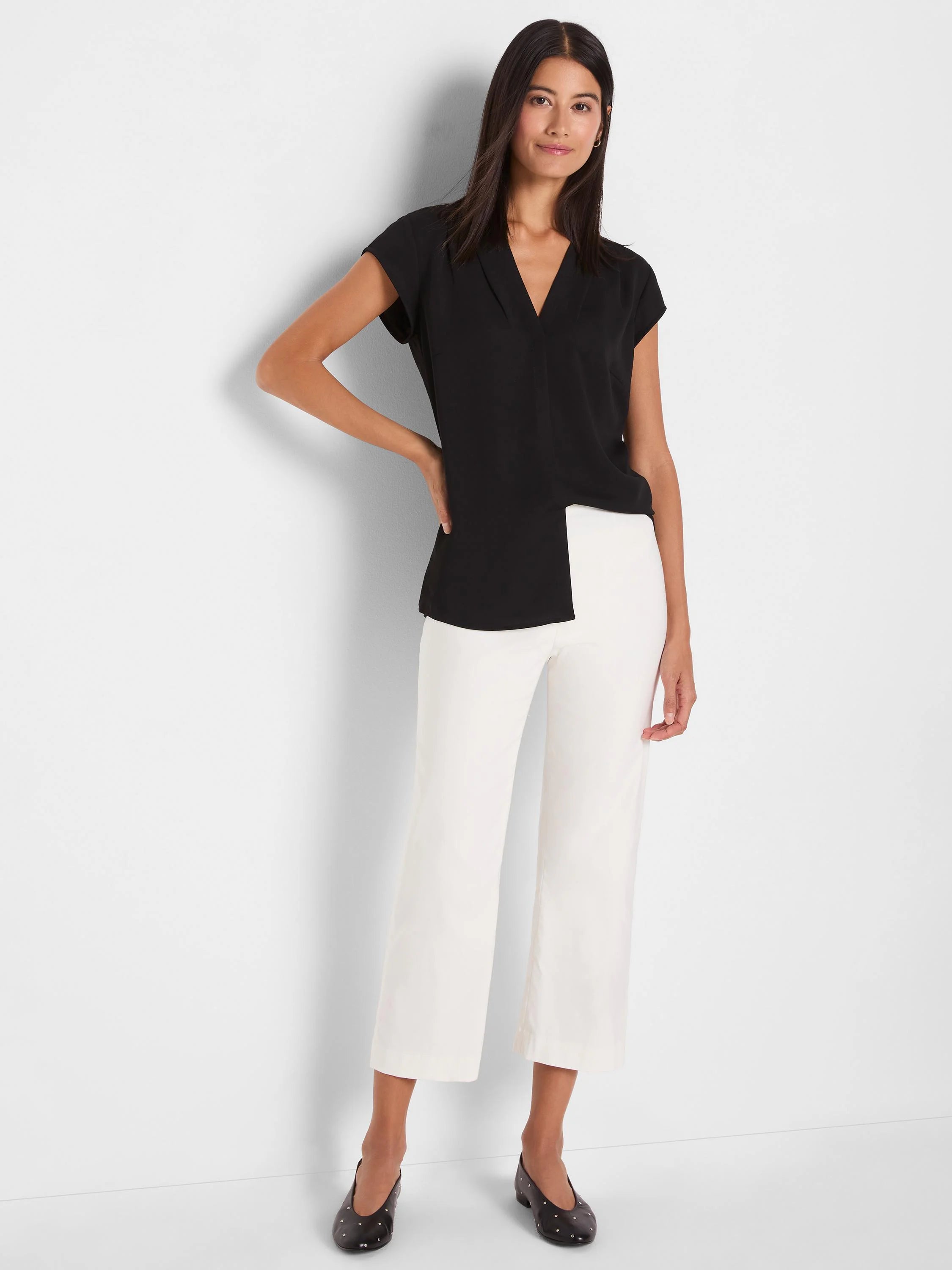 Black cap sleeve top with a lapel V-neck and an asymmetrical hem.