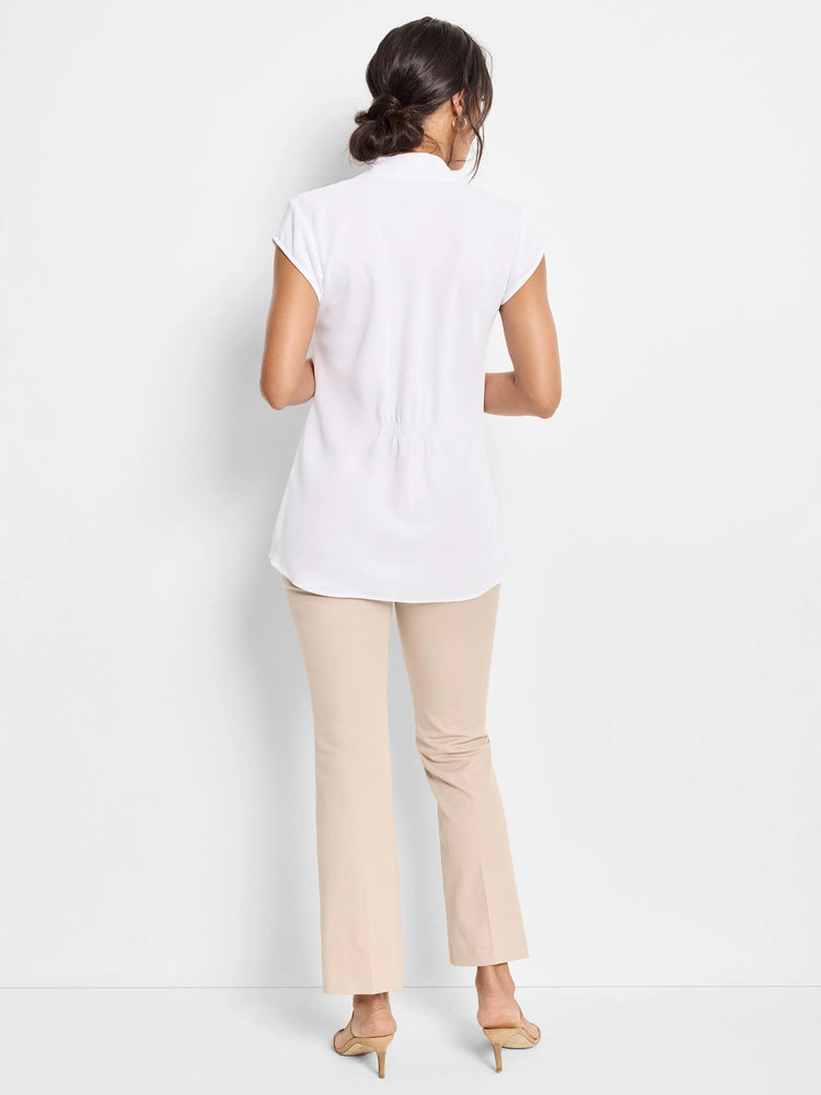 White cap sleeve top, seen from back. Features a stand collar, shirring at lower back, and rounded hem.