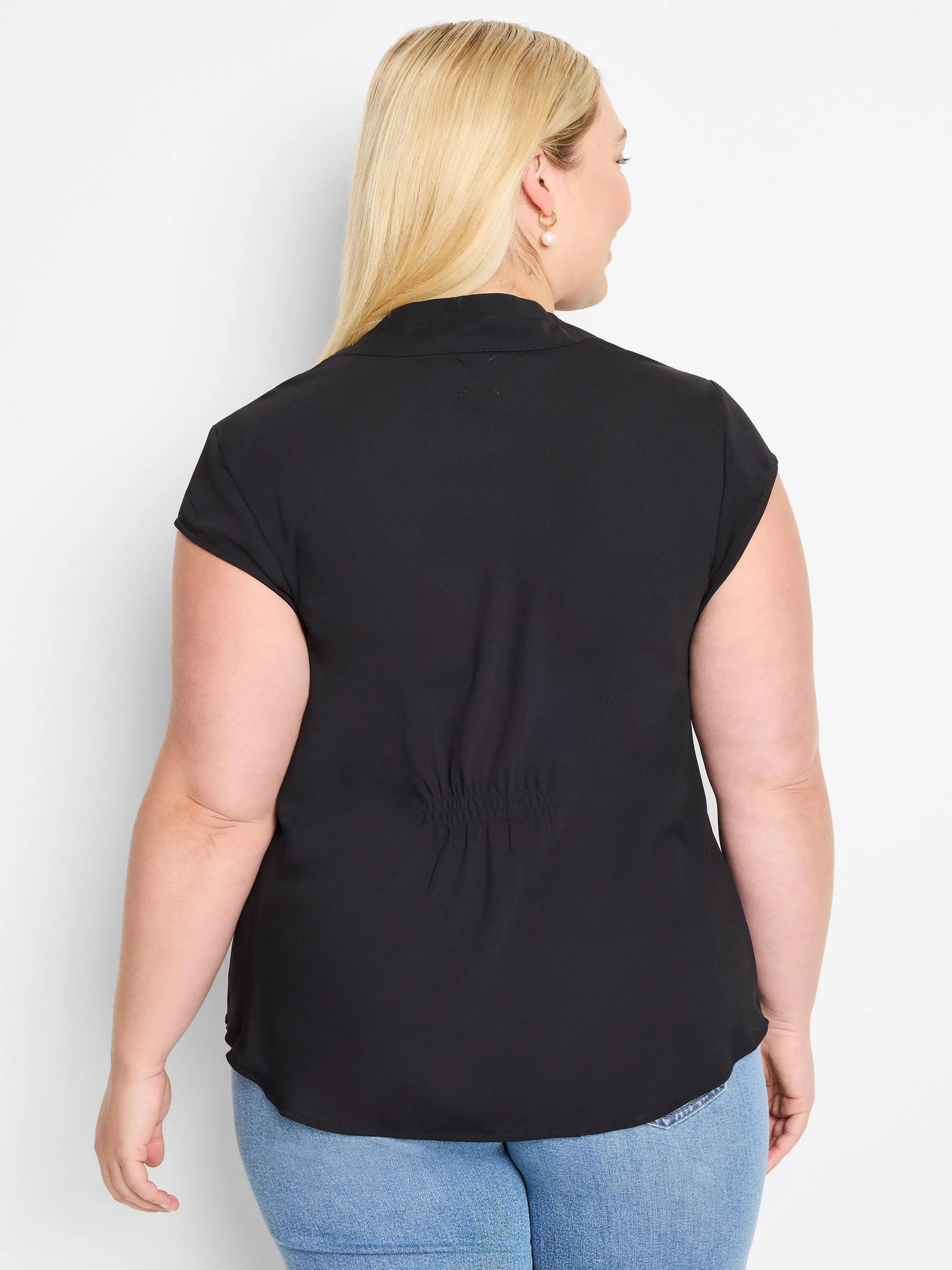 Black cap sleeve top from behind. Features a stand collar and shirred detail across the lower back.