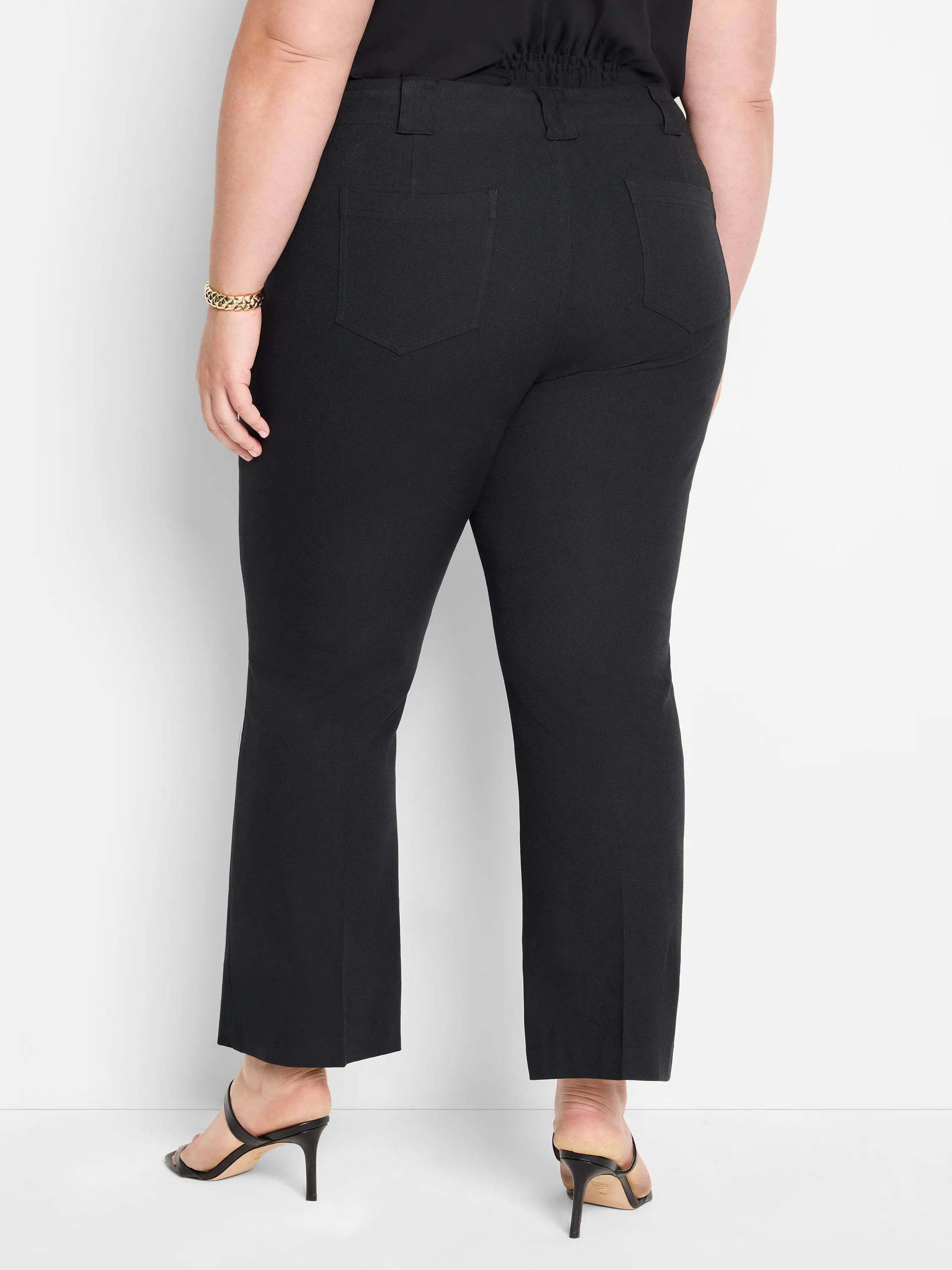 Black demi boot pants on a model, rear view. Features belt loops, two stitched back pockets, and a slight flare at the hem.