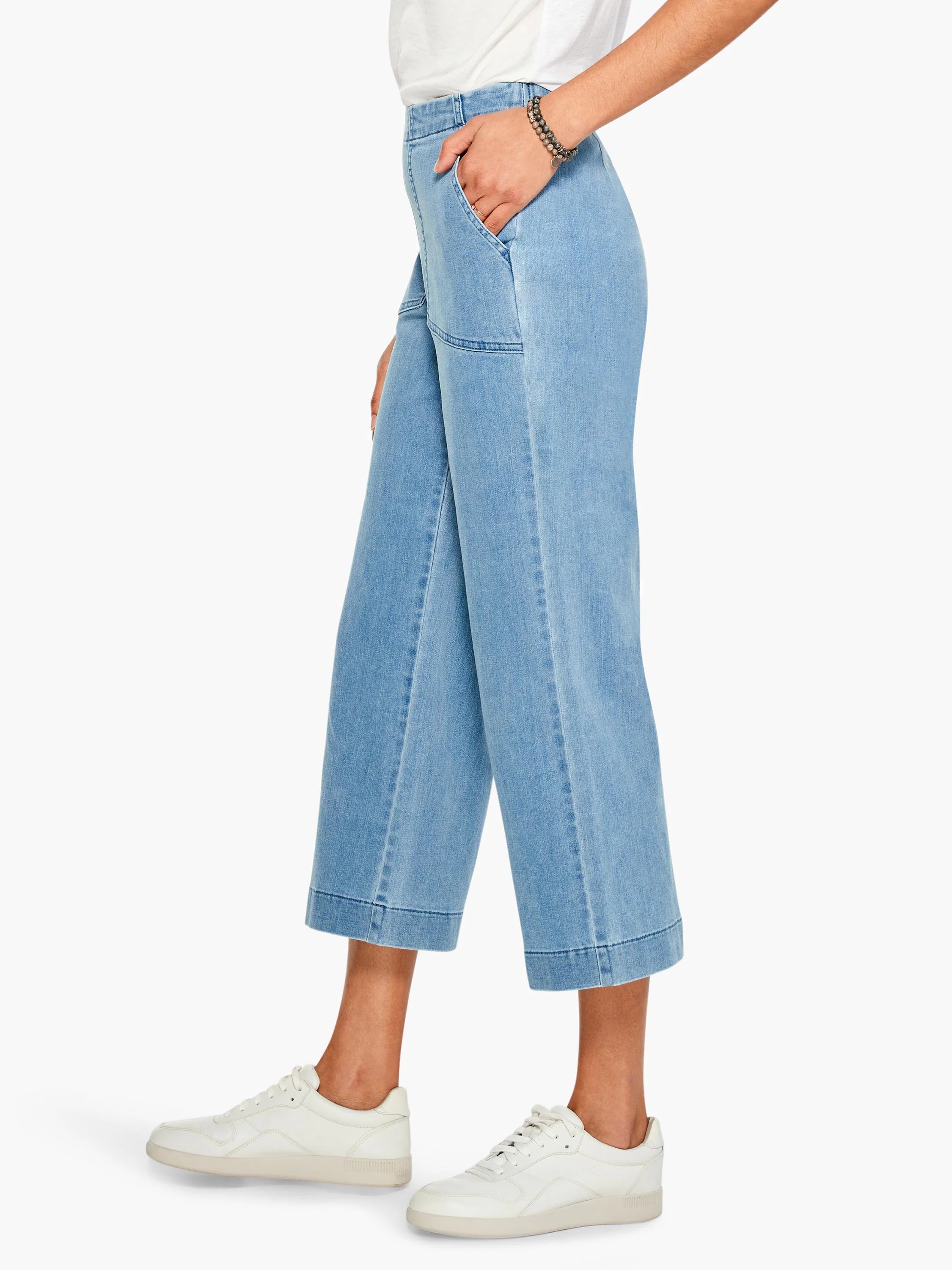 Light blue, wide-leg cropped jeans; cuffed hems. Model wears white sneakers.