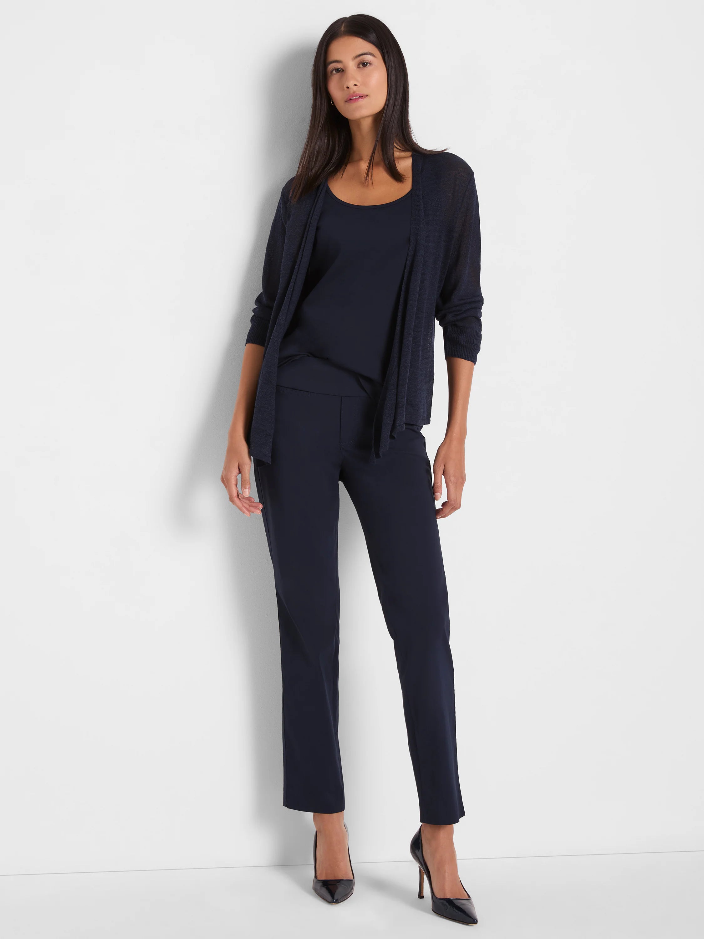 Woman wears navy blue straight leg pants with subtle pockets. They are ankle-length.