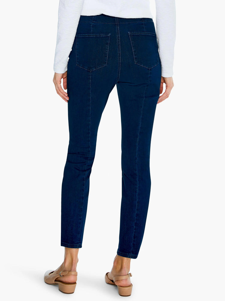 Dark wash, slim-fit jeans on a person, seen from behind. Features back pockets and vertical leg seams.