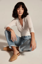 Light blue wash girlfriend jeans, mid-rise, cuffed at ankles. Model wears them sitting cross-legged.