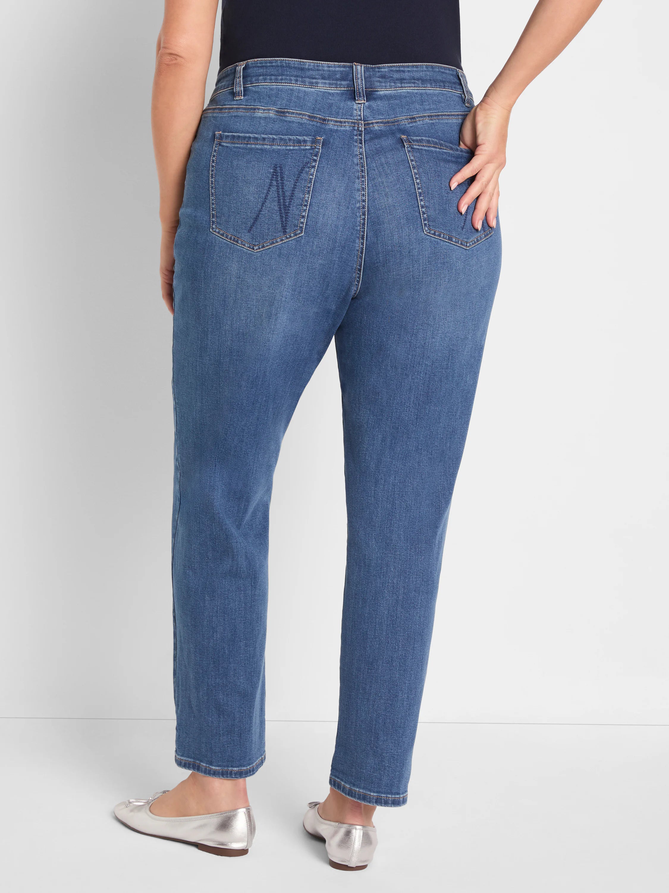 Medium blue girlfriend jeans, back view. Cropped cut, with back pockets; right pocket has an 'N' stitch.