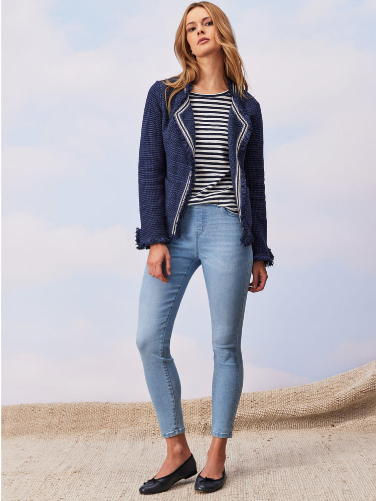 Navy textured jacket with contrast zip trim and fringe is paired with light wash slim jeans.