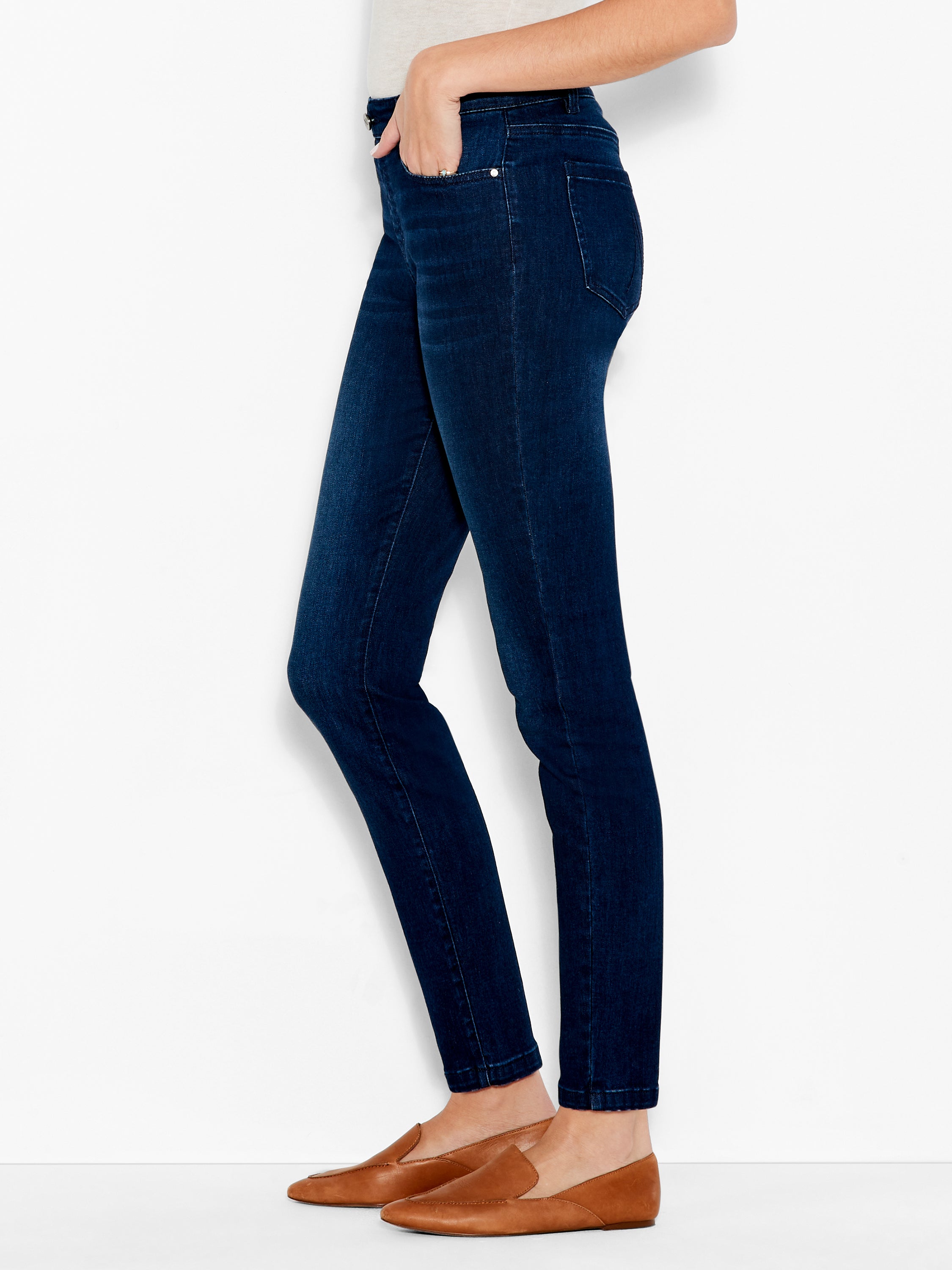 Dark wash skinny jeans are shown on the model, featuring a clean, tailored fit and minimal hardware.