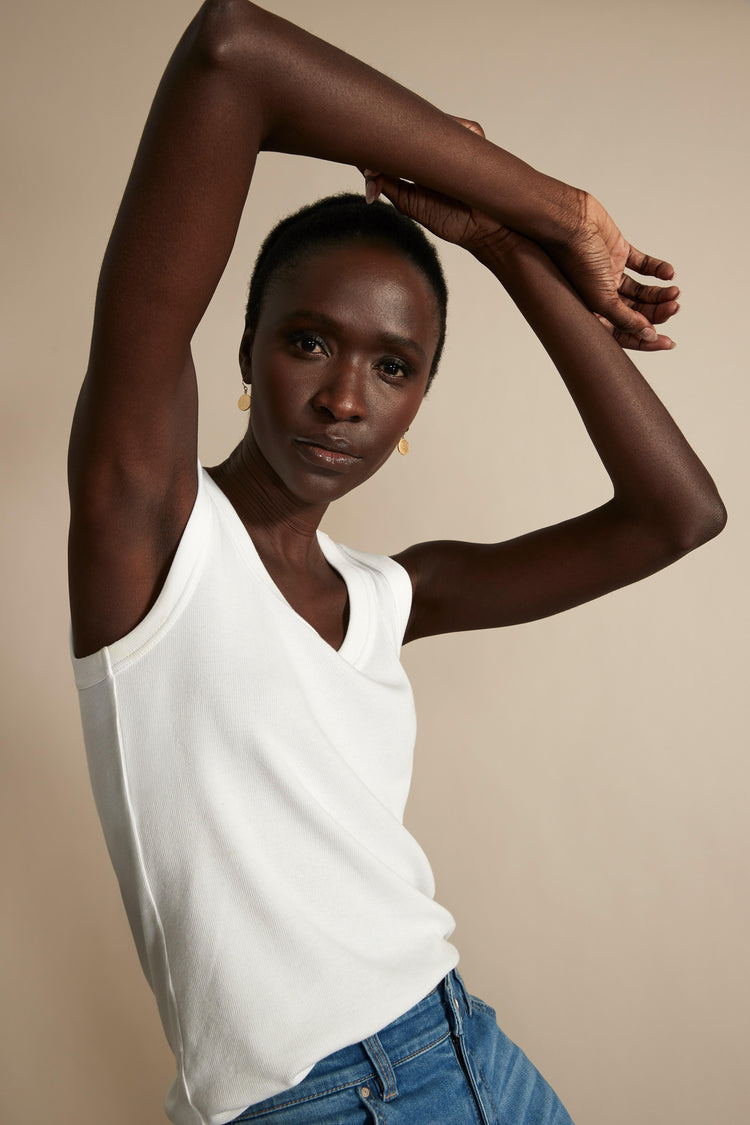 A fitted white ribbed tank top with a V-neck is shown on the model.