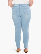 Faded light blue slim ankle jeans, rear view. Features two back pockets with subtle stitch details.