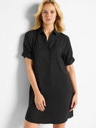 Smooth black shirt dress with collared V-neck, cuffed short sleeves, and a loose, above-the-knee length.