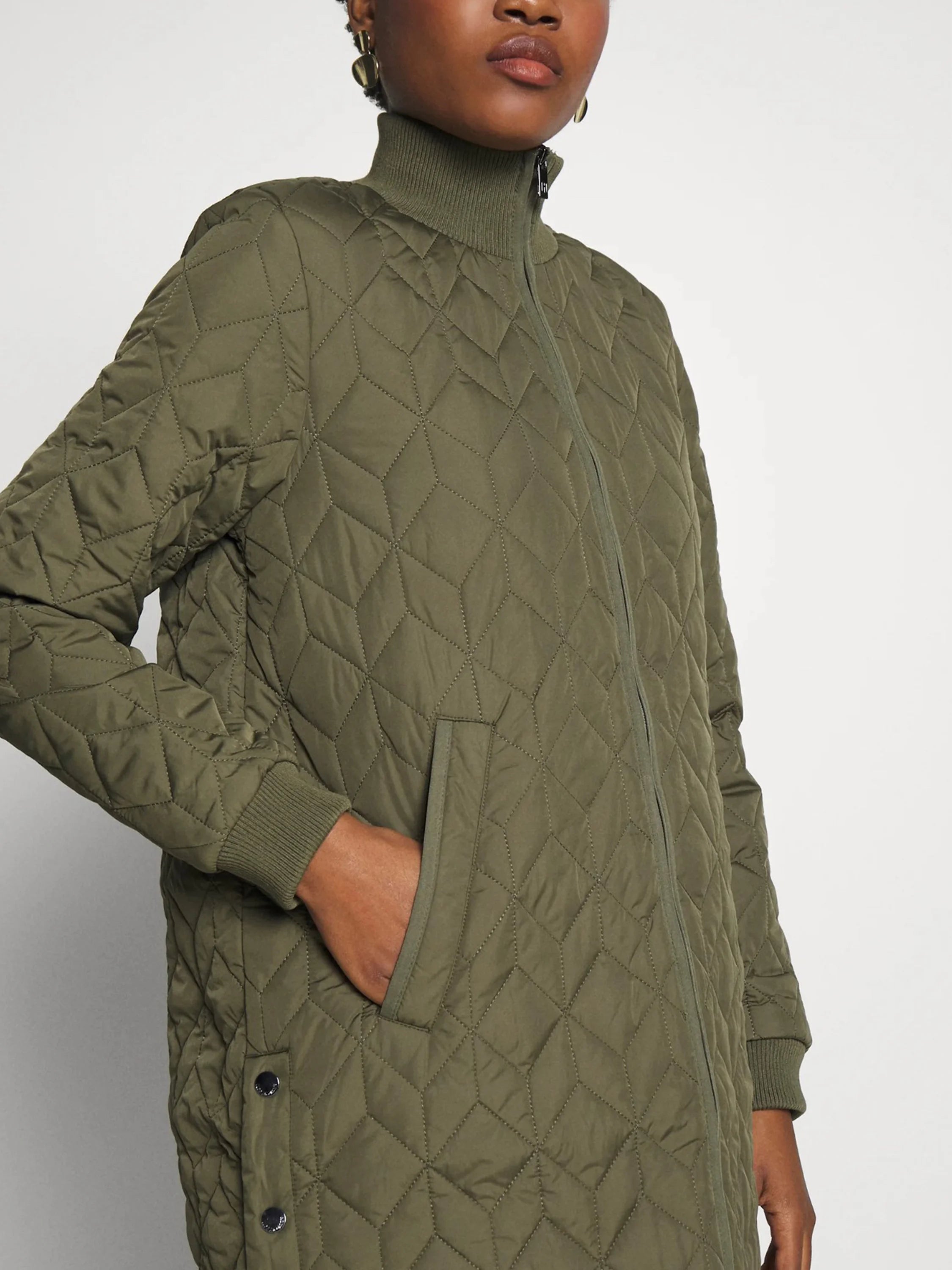 Olive green quilted coat, zip front, ribbed cuffs, and side pockets. Diamond quilting pattern.