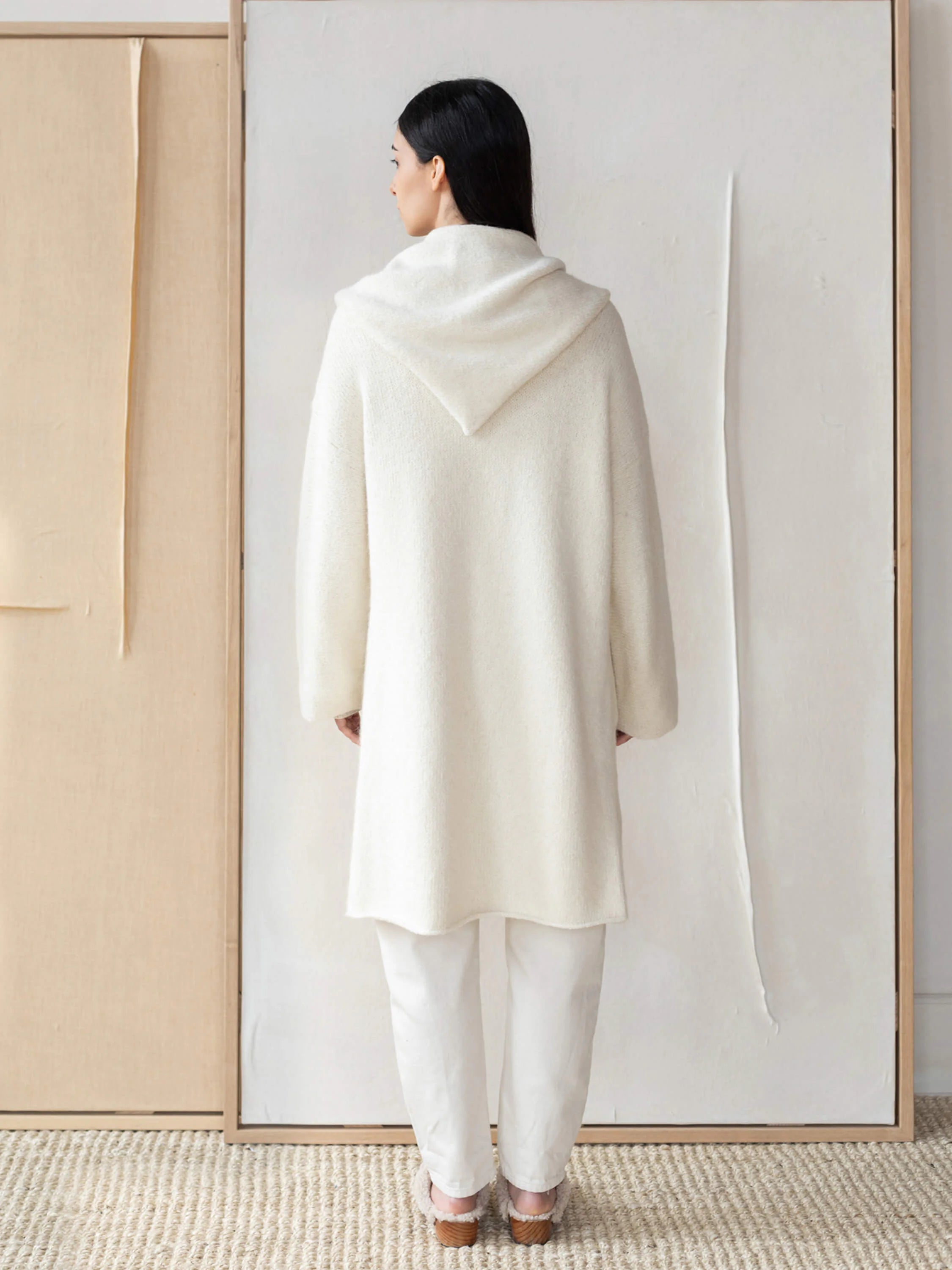 Off-white alpaca hooded coat, knee-length, shown from the back. Features a large hood.