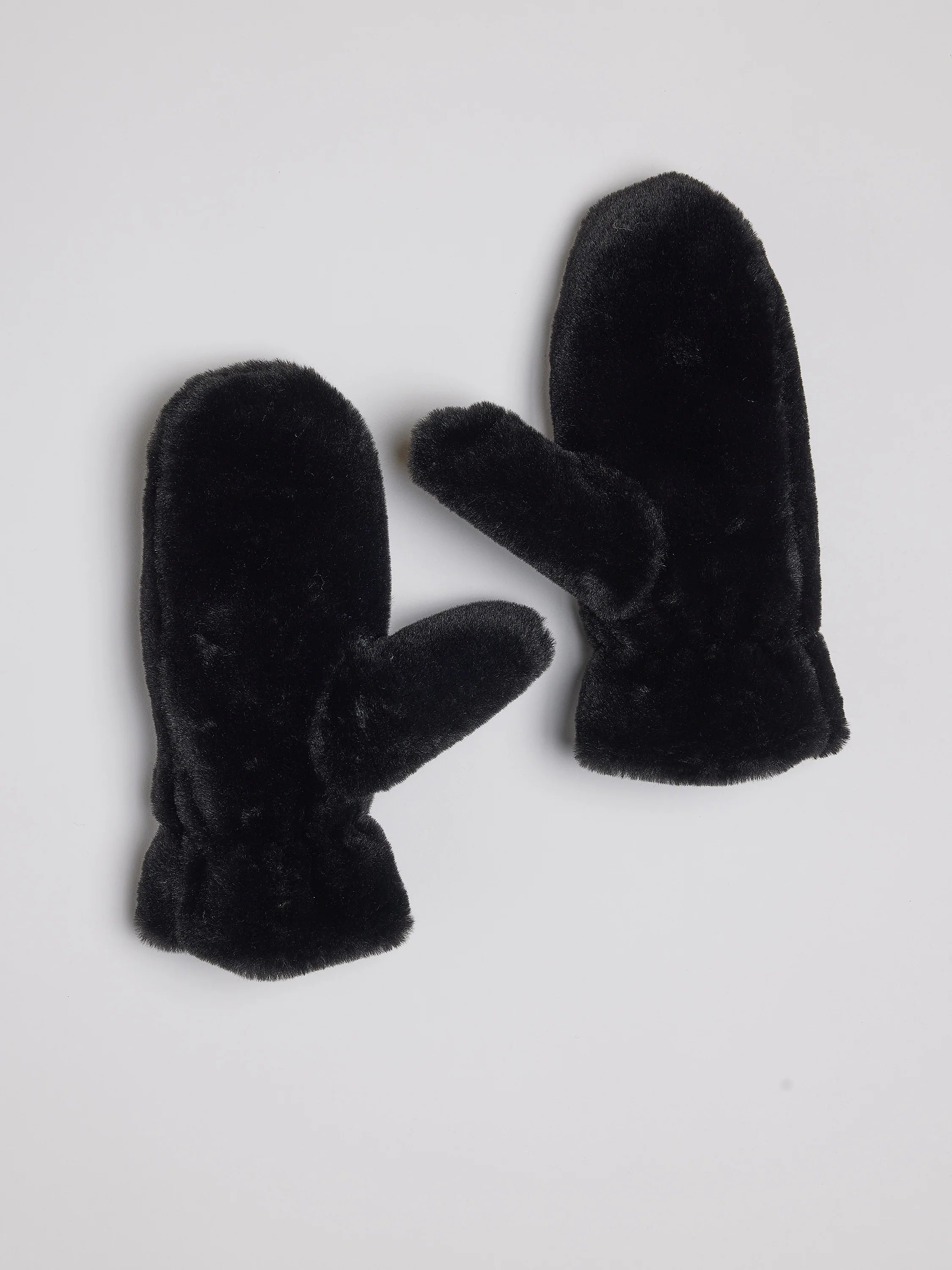 Pair of black faux fur mittens, fluffy texture, standard mitten shape with separate thumb, on light background.