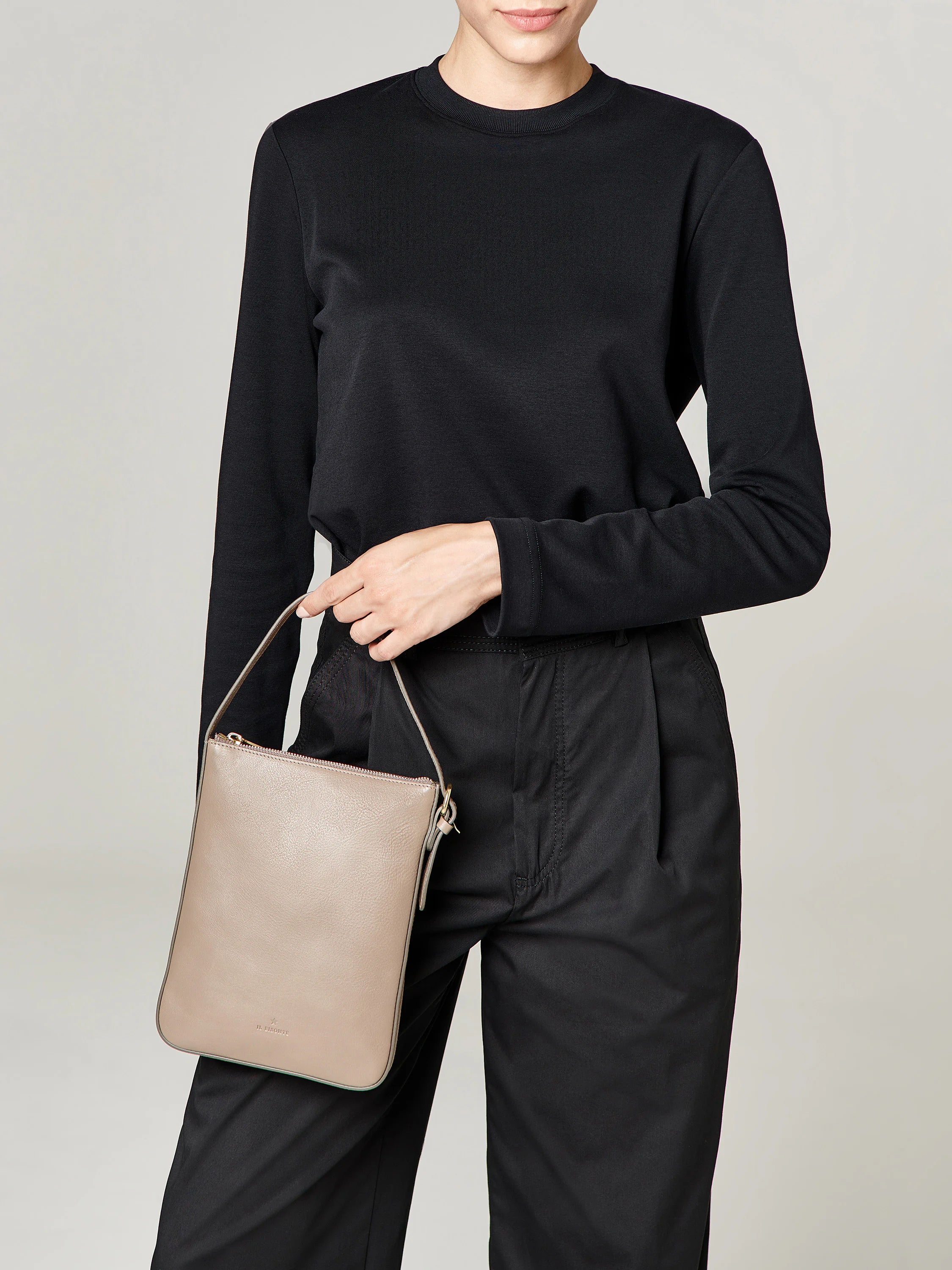 Beige rectangular crossbody bag with a top handle and zipper. Subtle branding.