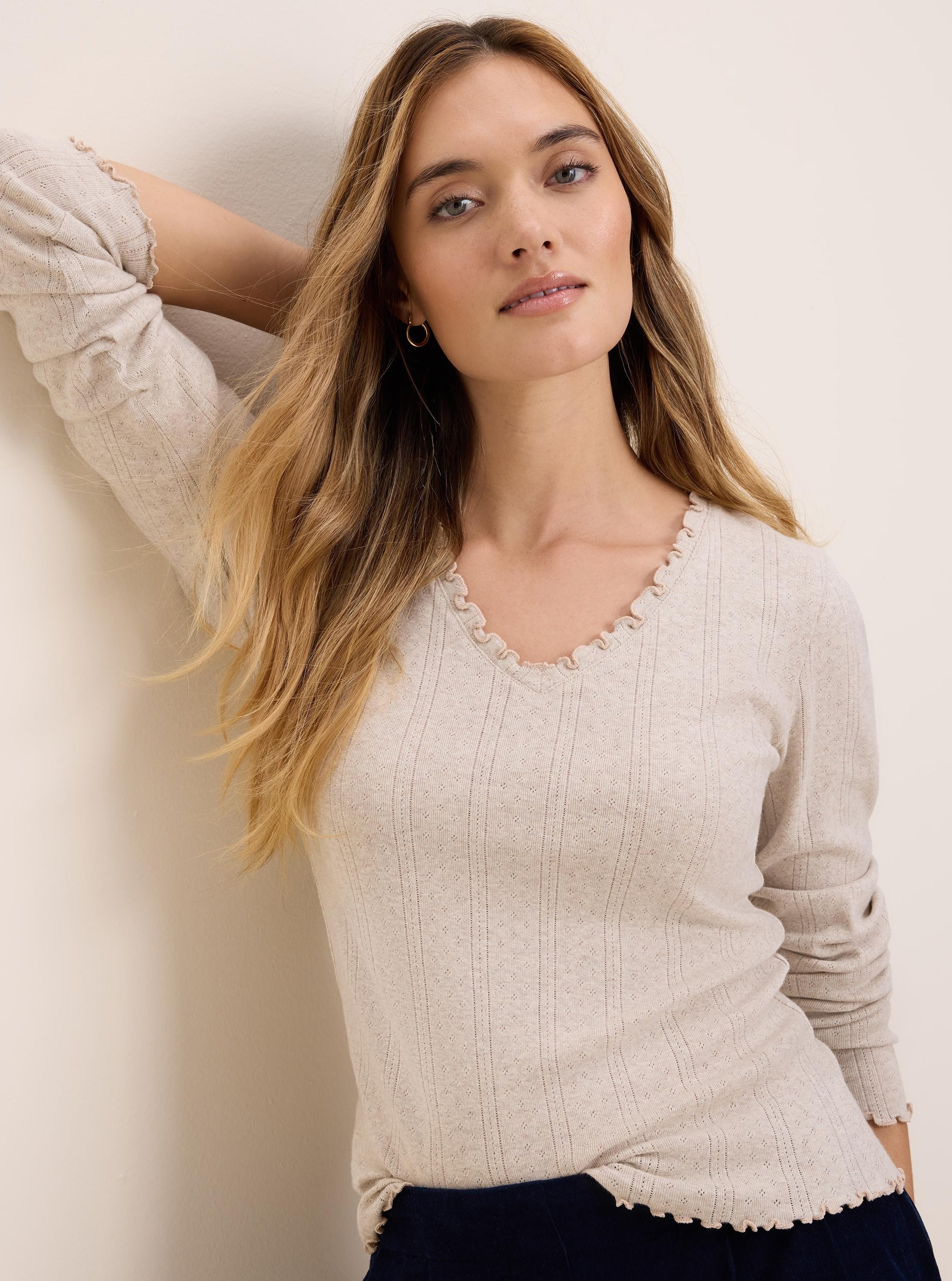 Pale beige pointelle rib long sleeve tee with ruffled V-neck, cuffs, and hem.