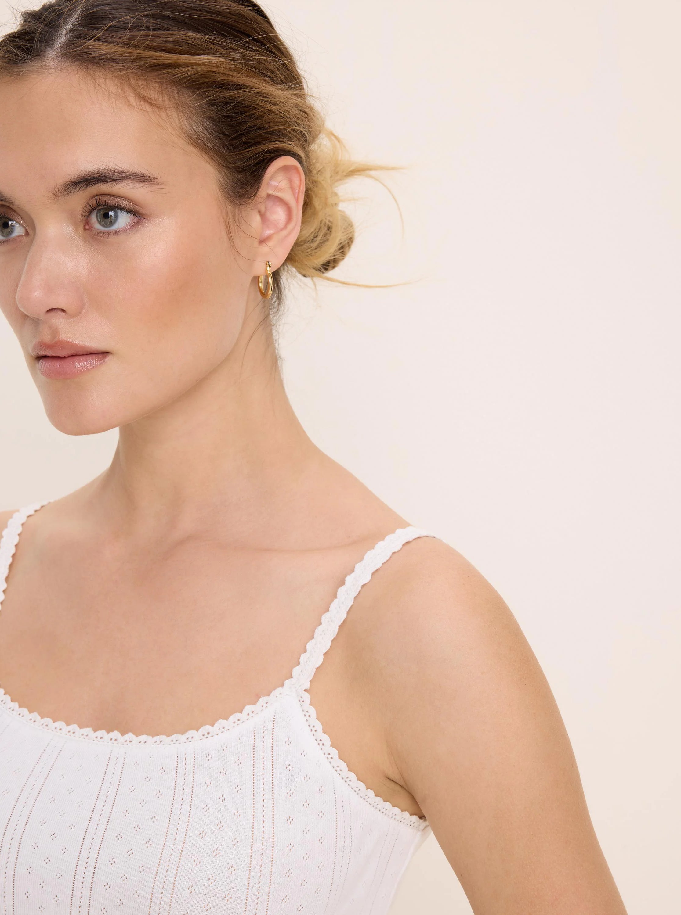 White pointelle rib cami with thin straps and scalloped lace trim on the neckline and straps.