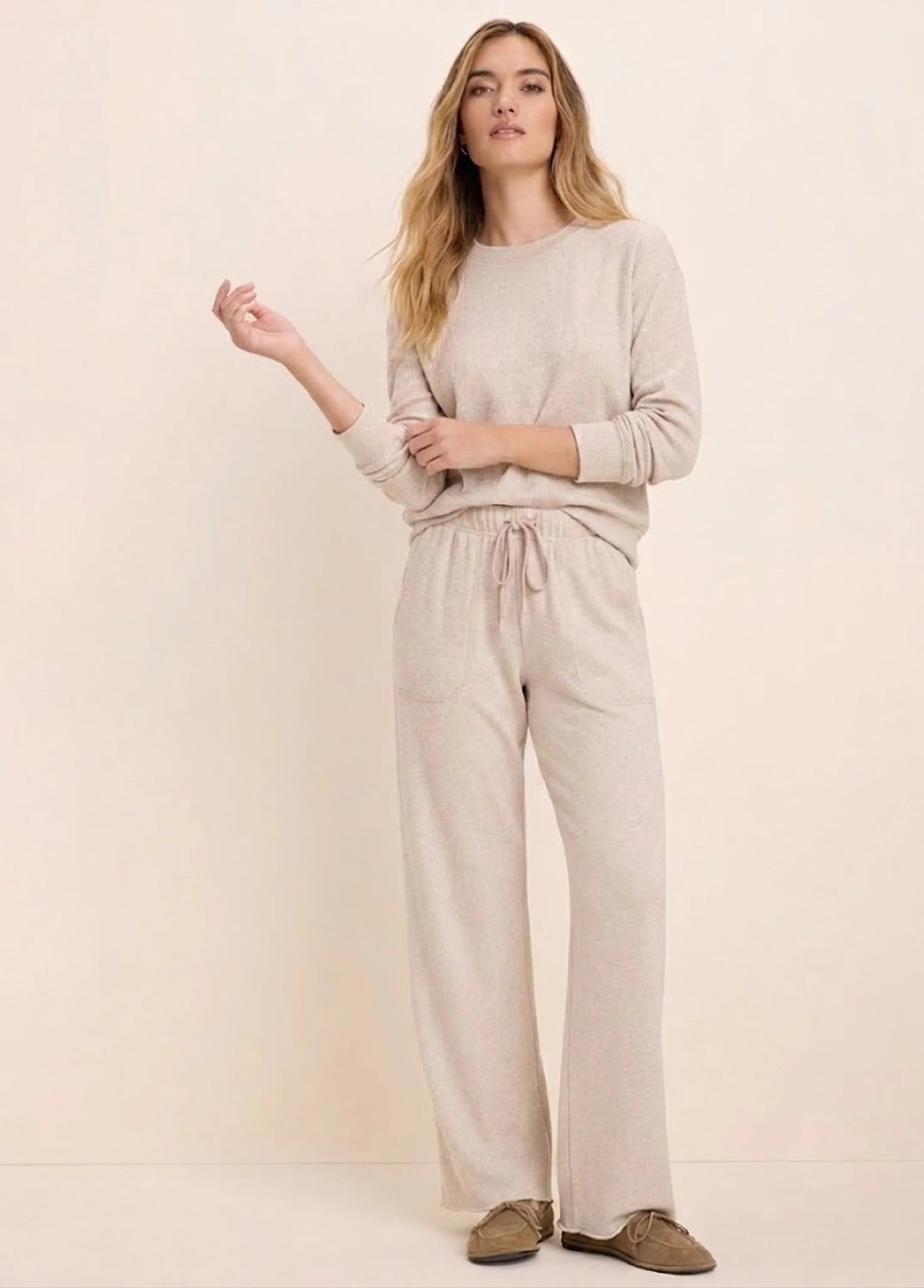 Model wears a light beige ribbed cotton terry crew neck top with long sleeves, paired with matching drawstring pants.