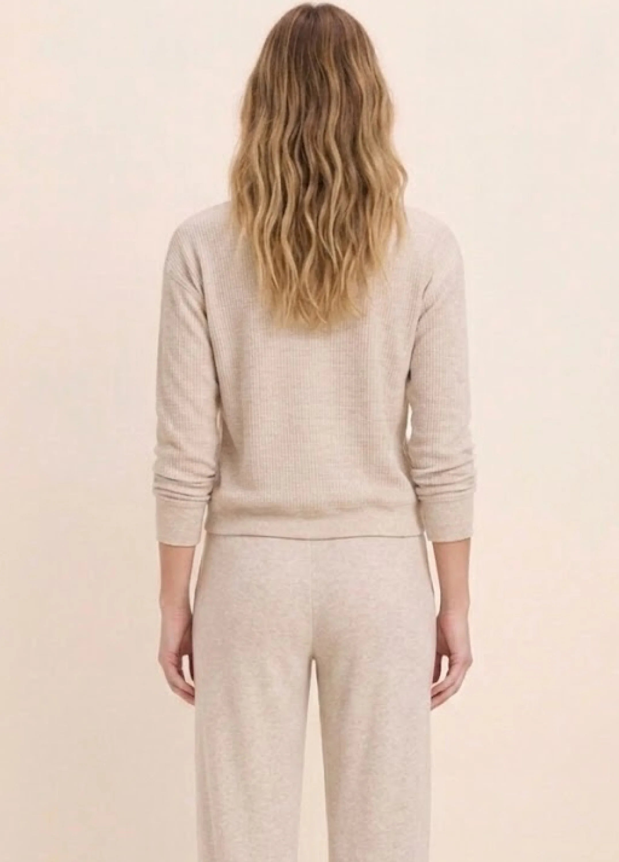 Back view of a model in a light beige, ribbed cotton terry crew neck long-sleeve top.