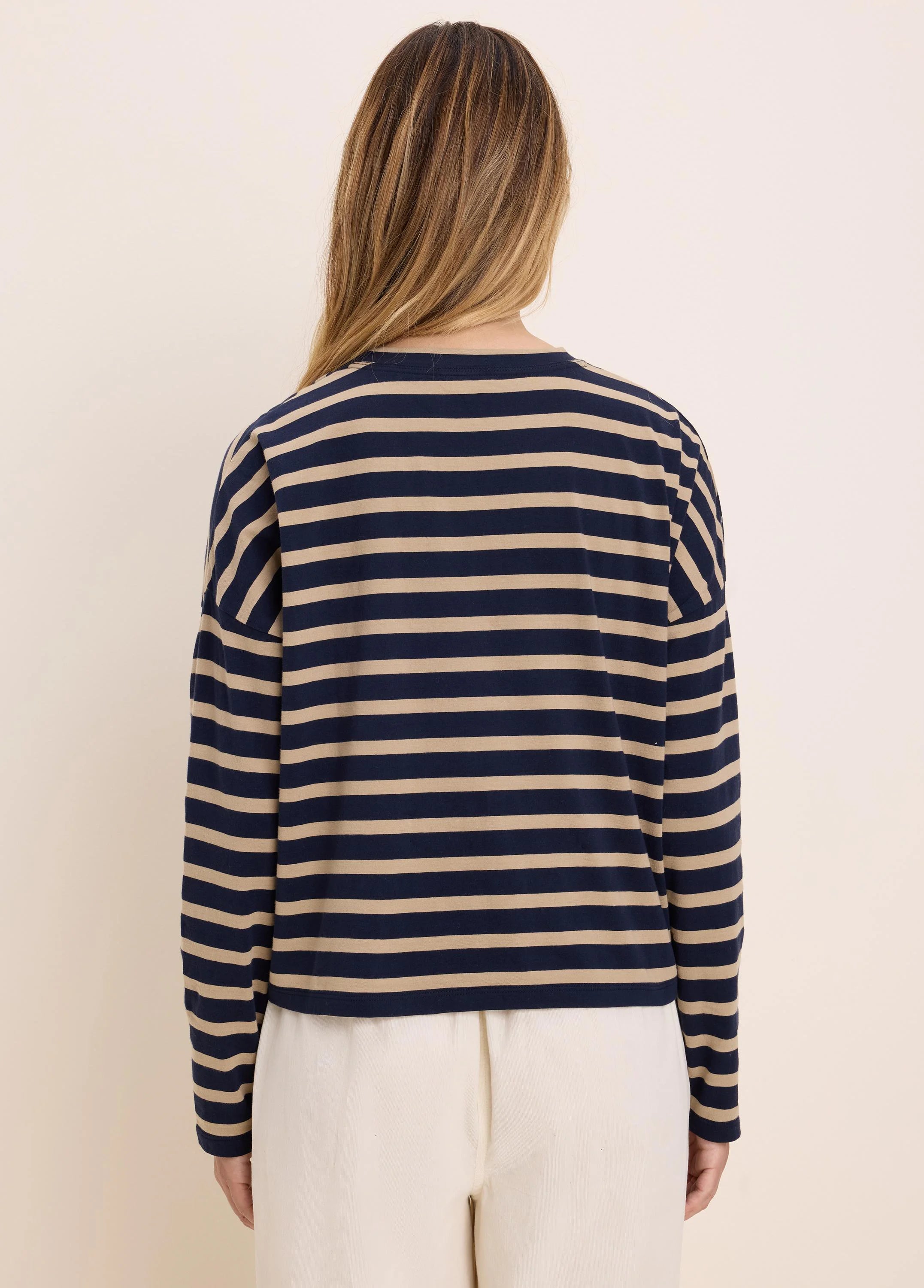Long-sleeved tee with horizontal navy blue and beige stripes. Model from behind.