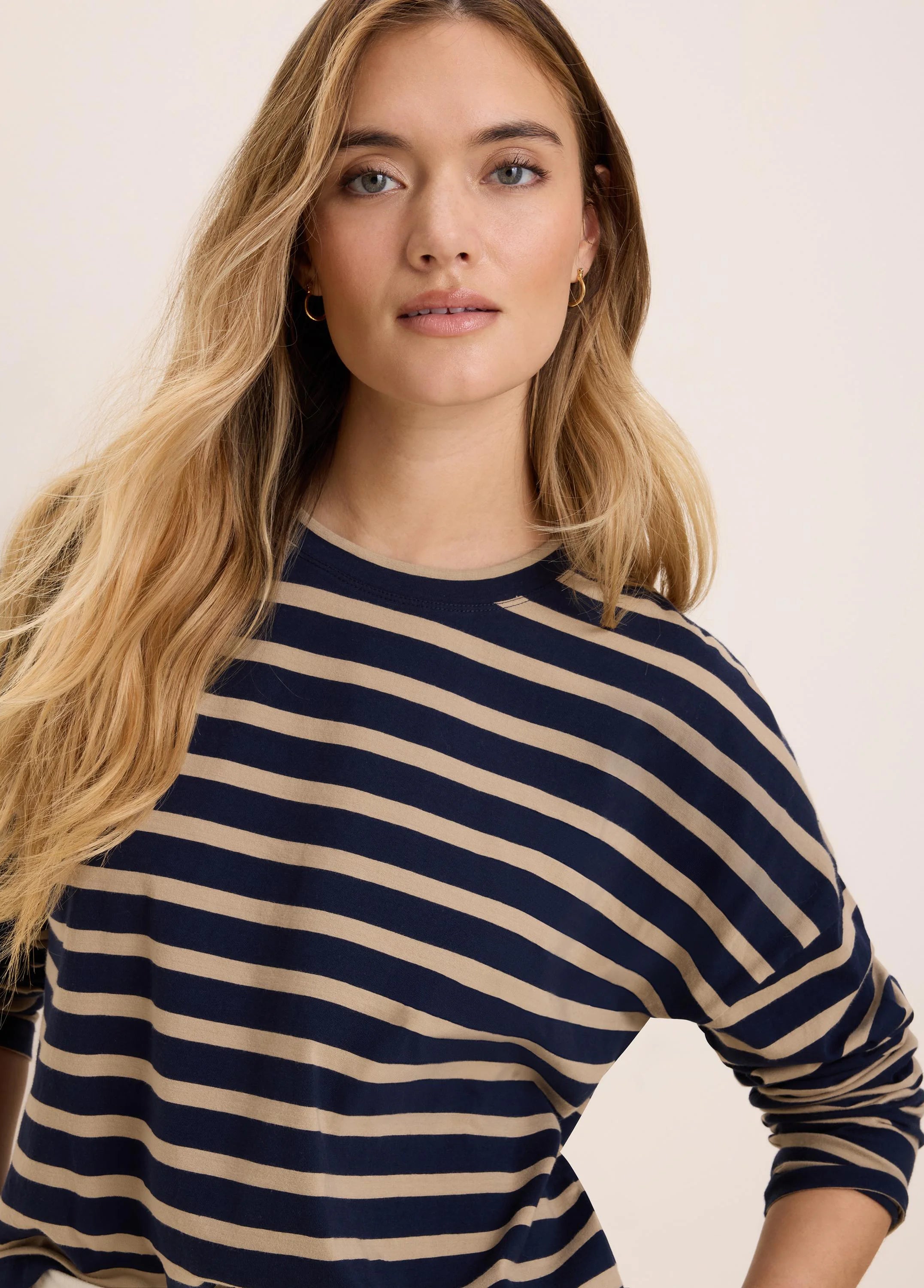 Navy and light beige horizontal striped long-sleeve crew neck tee.