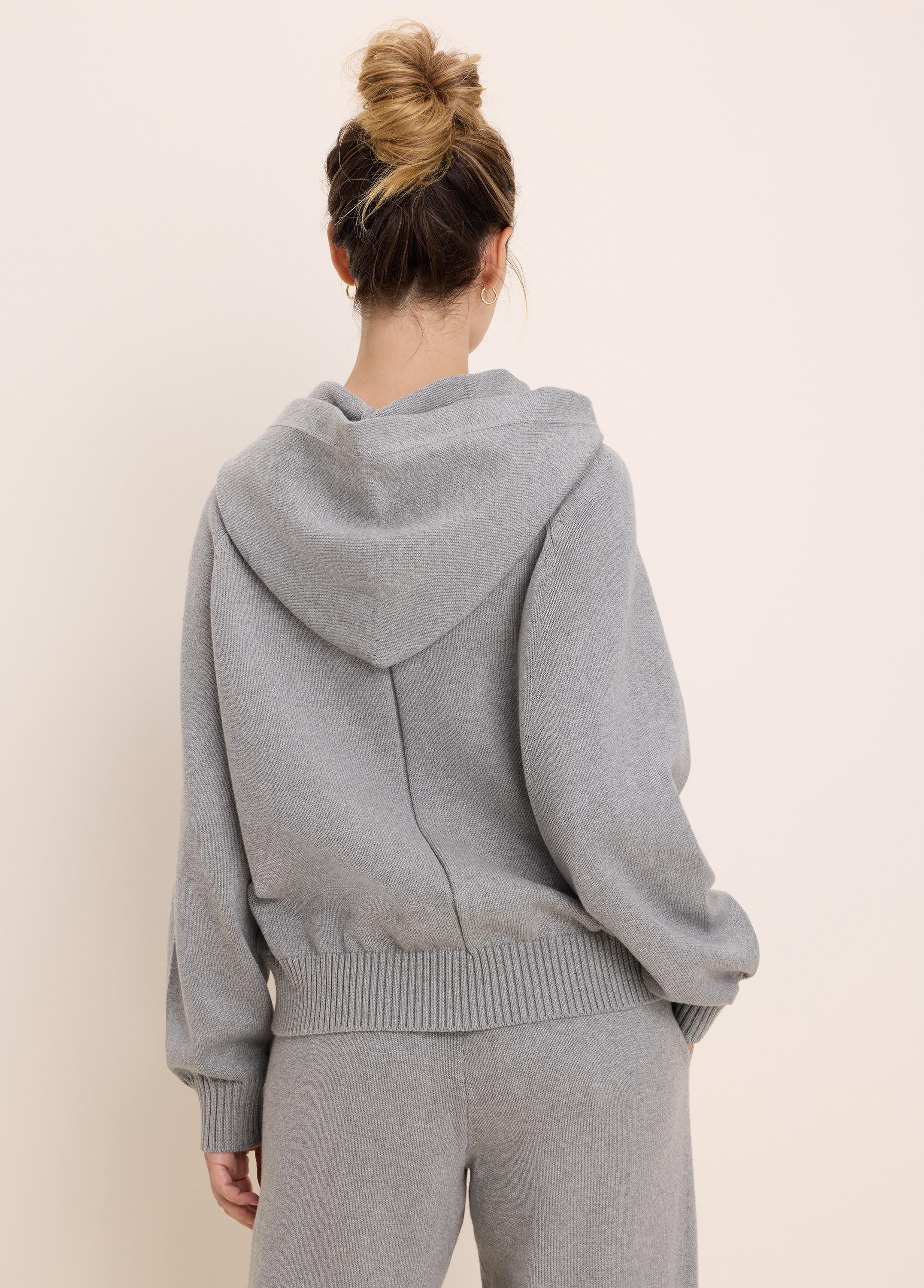 Light gray knit sweater hoodie, viewed from the back. Features a hood, ribbed cuffs, and a ribbed hem.
