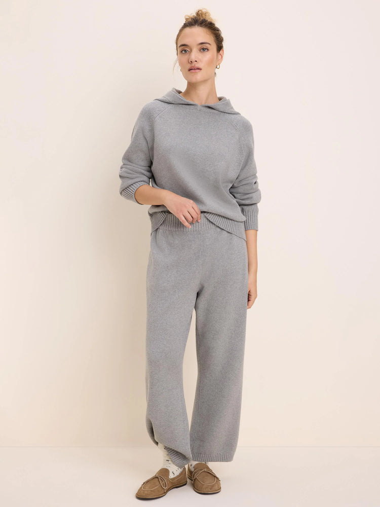 Light gray knitted sweater hoodie with ribbed cuffs and hem, modeled with matching wide-leg pants.