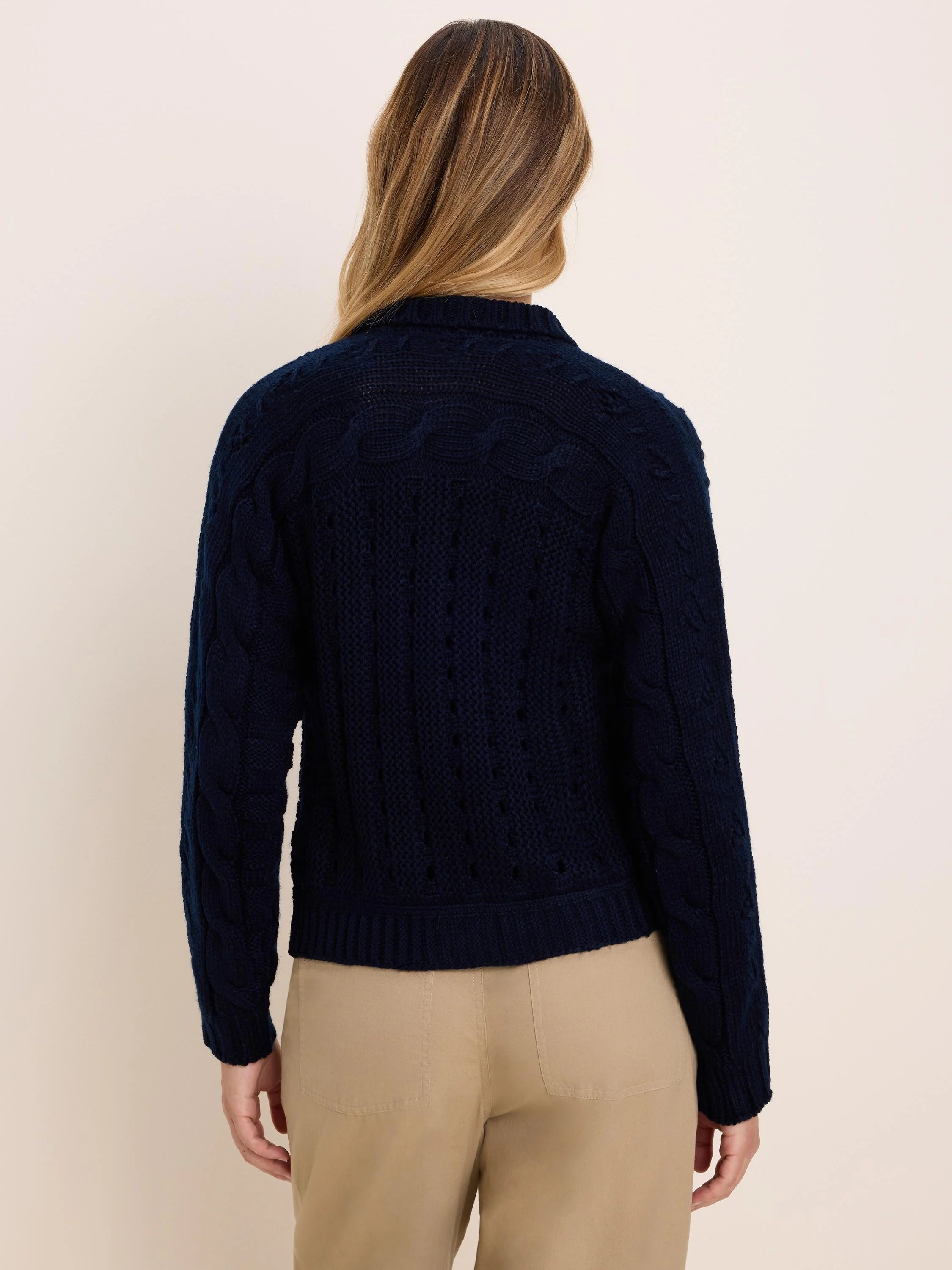 Navy blue cable knit cardigan, back view on model. Features classic cables and varied open-knit patterns.